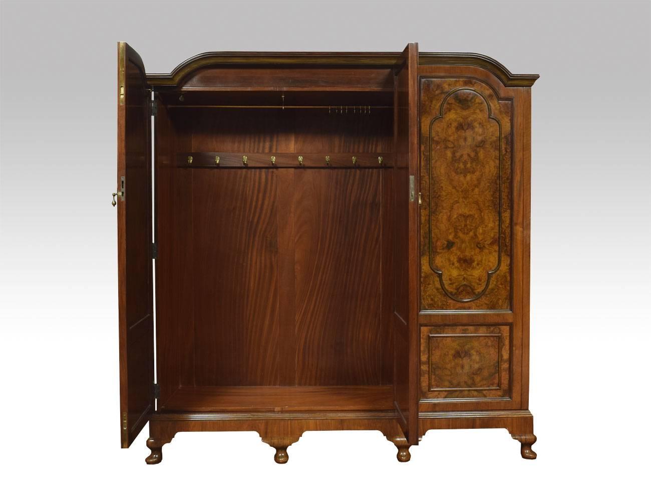 Walnut three door combination wardrobe, the shaped cornice above three long paneled burr walnut doors opening to reveal large hanging area to one side the other fitted with sliding trays and draws. All raised up on cabriole