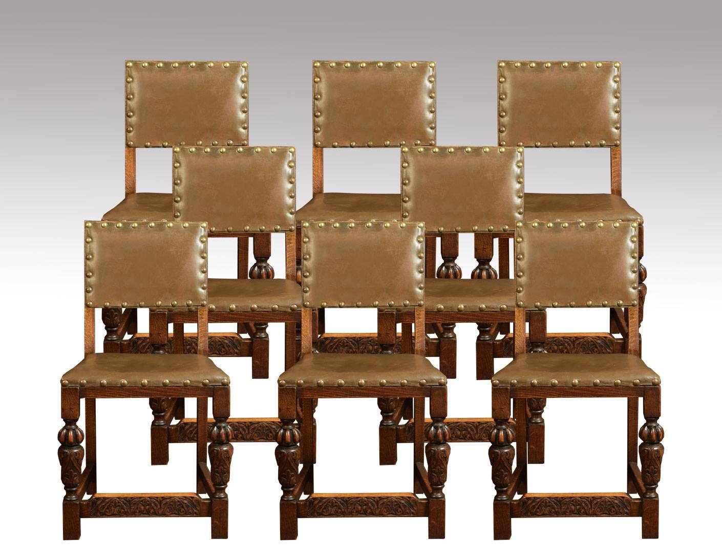 

Set of ten carved dining chairs comprising of eight chairs and a matched set of two armchairs the square upholstered studded backs above overstuffed seats the carvers with scrolling arms all raised up on turned front legs united by