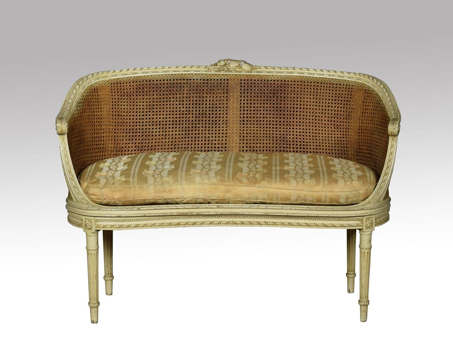 French Louis XVI style canape´ settee, the carved rail in the typical manner of the period with highly detailed ribbon work along the crest among foliage, the frame a repeating motif of detailed leaves. To the scrolling acanthus caped arms, flanking