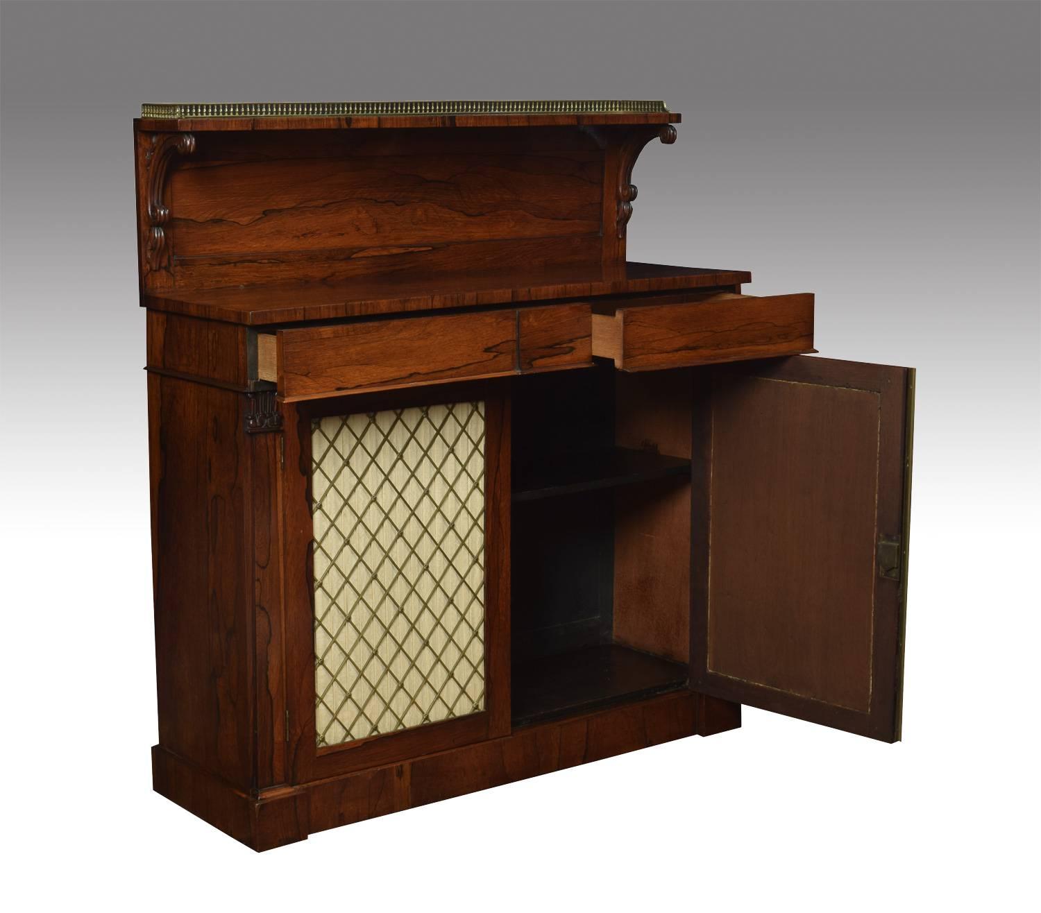 Regency rosewood two-door chiffonier, the raised gallery back with reeded scroll supports above two short freeze draws the base section fitted with two silk panelled doors behind brass grilles. The doors opening to reveal a single fixed shelf all