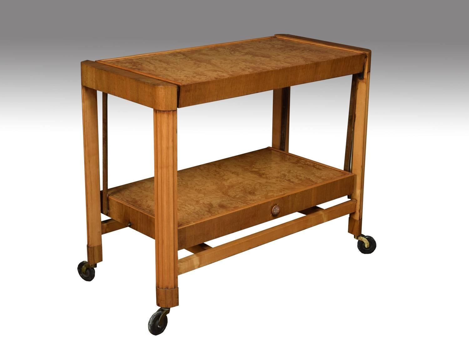 Art Deco metamorphic trolley. It comprises of a top shelf and an under-shelf which folds up on a cantilever to create a tabletop. Supported on four curved reeded supports terminating in castors.

Dimensions:
Height 26 Inches,
length 31.5