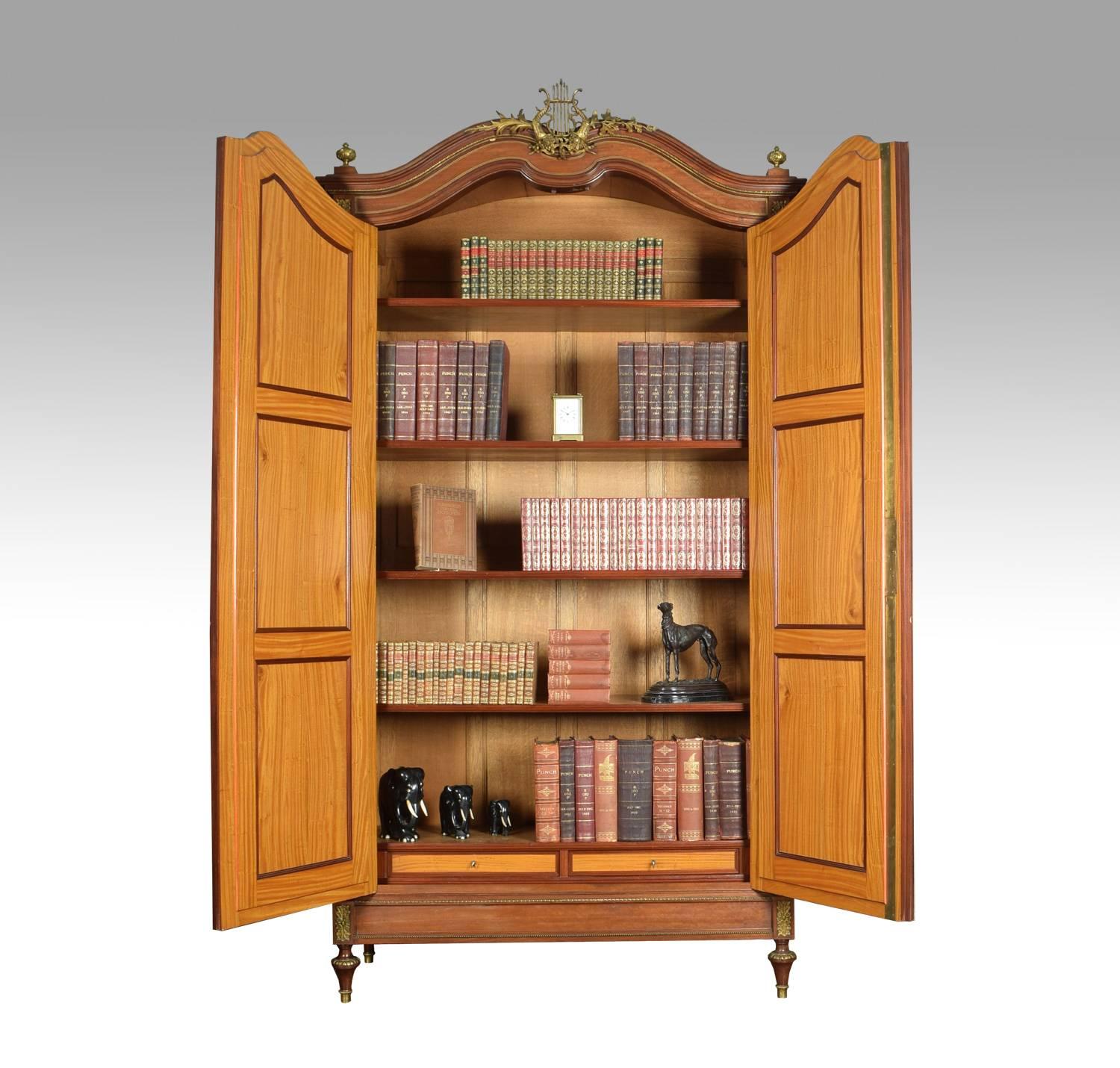Late 19th century, French mahogany bibliotheque. The moulded cornice with central lyre motif above two large mirrored doors enclosing four adjustable shelves with two short draws below. All raised up on tapering brass caped feet. The bibliotheque