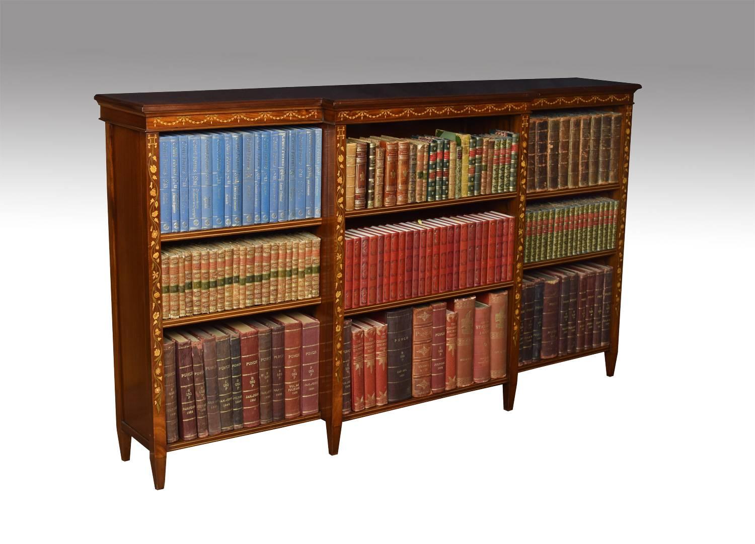 Edwardian mahogany and marquetry open bookcase, the large breakfront string inlaid top above three bays of adjustable shelves, each section having two shelves. Divided by floral marquetry inlaid columns. Terminating in tapered