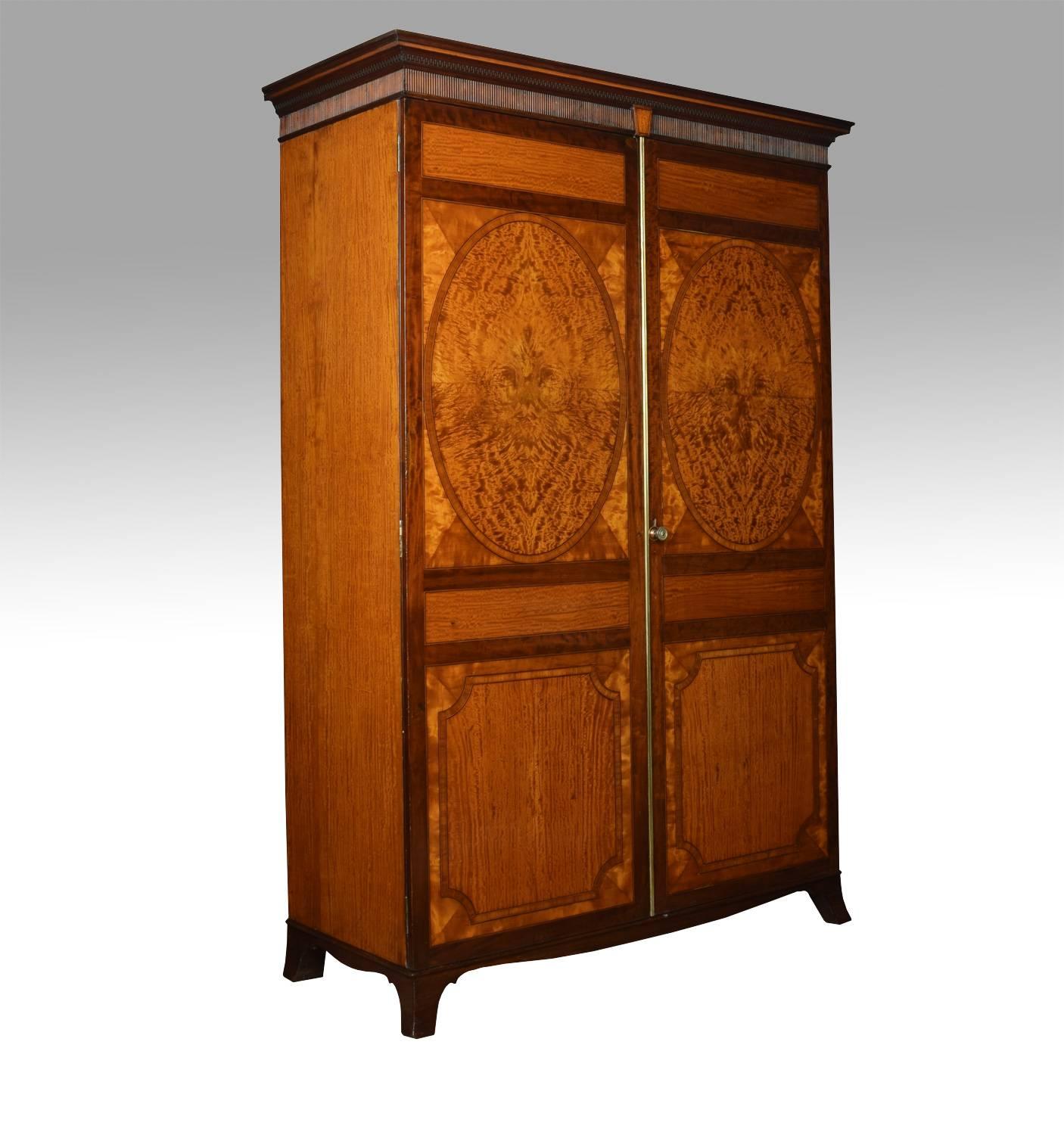 Satinwood two-door wardrobe, the moulded cornice, above two oval inlaid panelled doors, opening to reveal large hanging area. All raised up on shaped bracket feet

Dimensions
Height 81.5 inches
Width 64 inches
Depth 24 inches.