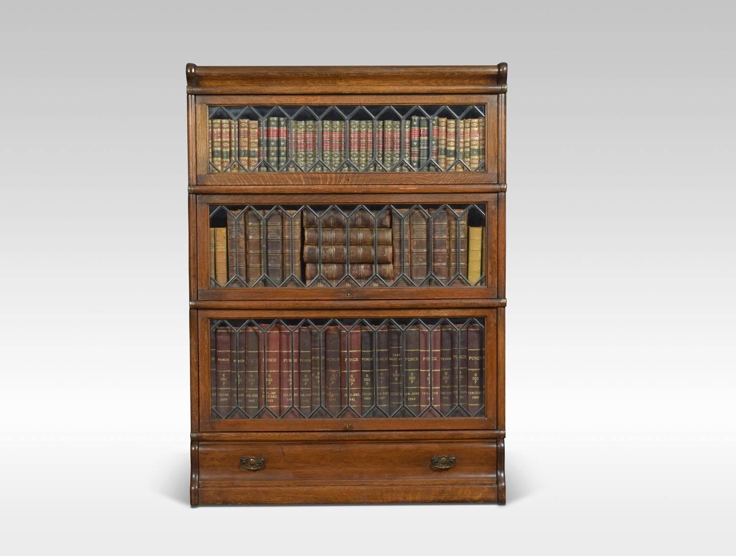 Oak globe Wernicke three section bookcase, the moulded top above three graduated section all having glazed doors, raised on a plinth base with single long draw.
Dimensions:
Height 47 inches
Width 34 inches
Depth 12 inches.