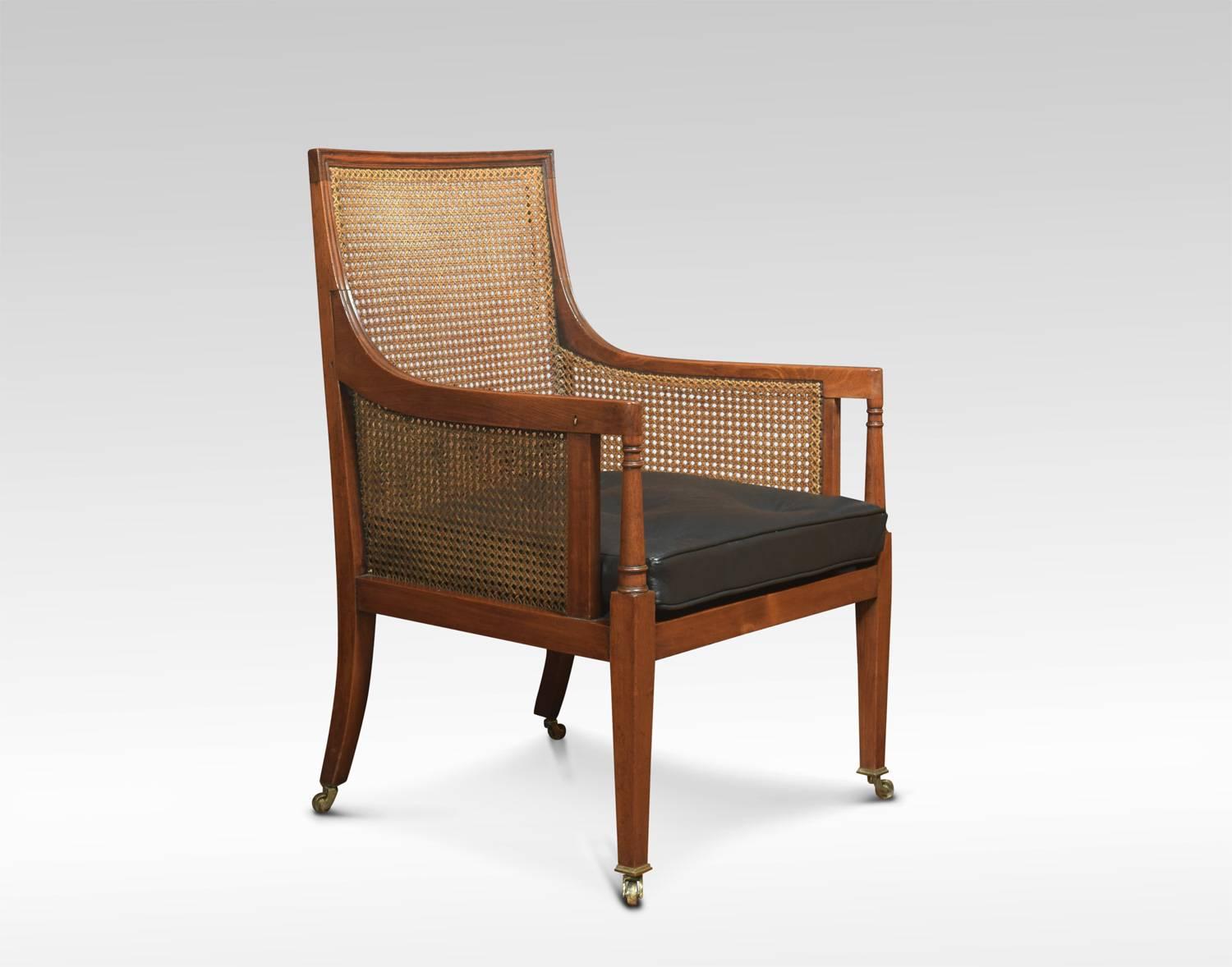 Edwardian Bergere armchair, the solid mahogany frame and inset bergere back and seat with removable black leather cushion. Raised up on turned tapering legs. Terminating in brass caps and castors.

Dimensions:
Height 37 height to seat 18