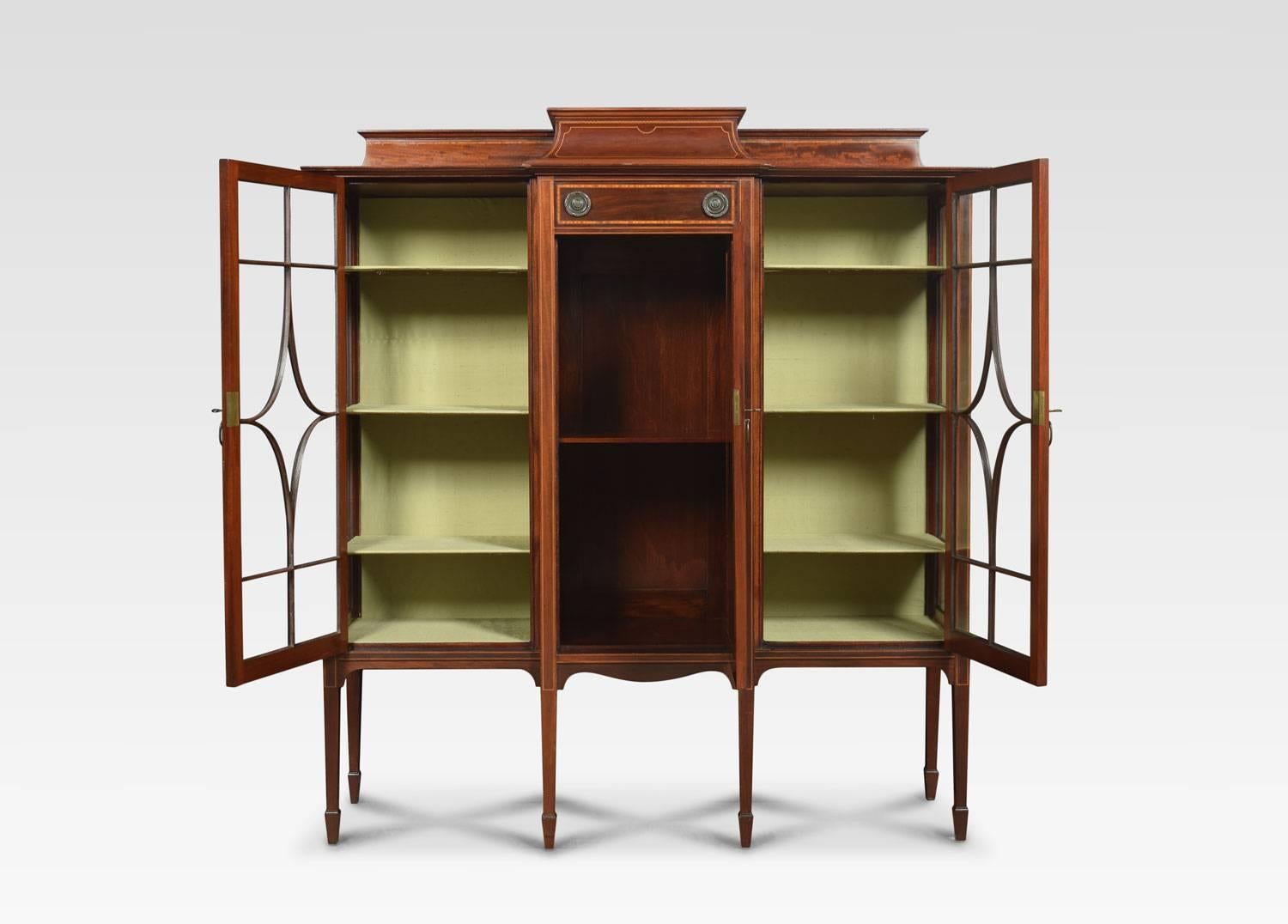Edwardian mahogany breakfront display cabinet, The raised three quarter gallery having a central short drawer, crossbanded with satinwood. Over an inlaid recessed panel cupboard door opening to reveal single fixed shelf flanked on either side with