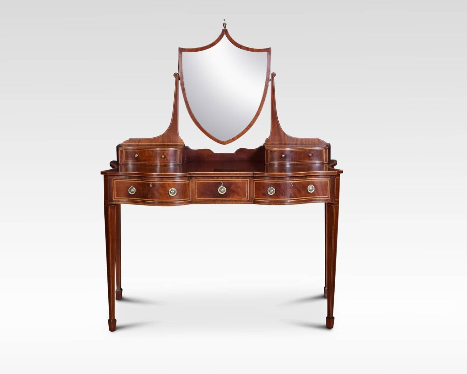 Edwardian Mahogany string inlaid dressing table, having a tilting shield shaped mirror with urn finial, raised on shaped supports, flanked by two short drawers. The kingwood crossbanded shaped dressing tabletop above three freeze draws fitted with