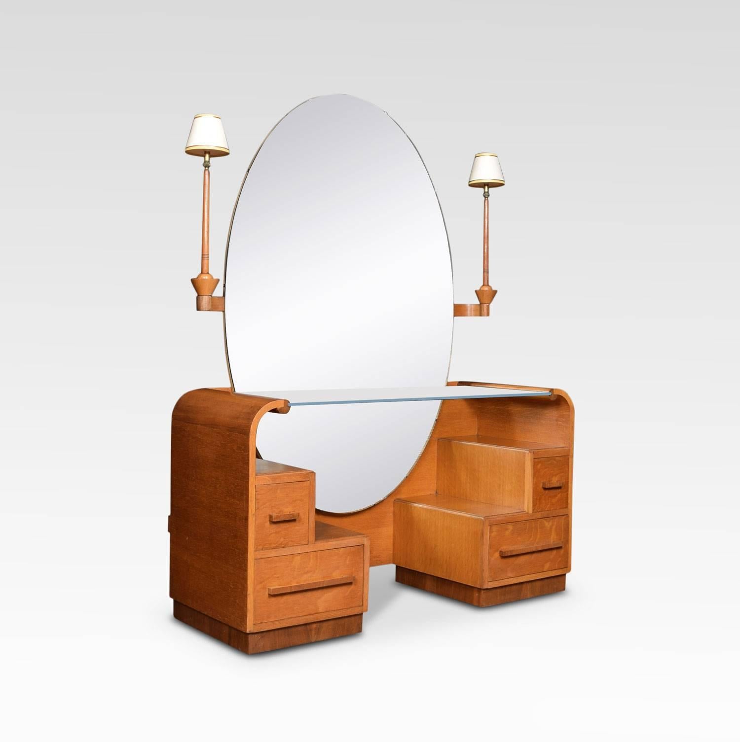 Art Deco oak dressing table, the large oval banded mirror plate flanked by out-swept sconces. To the base with large glass shelf above an arrangement of stepped draws and shelves.
Dimensions:
Height 64.5 inches
Width 48 inches
Depth 22 inches.