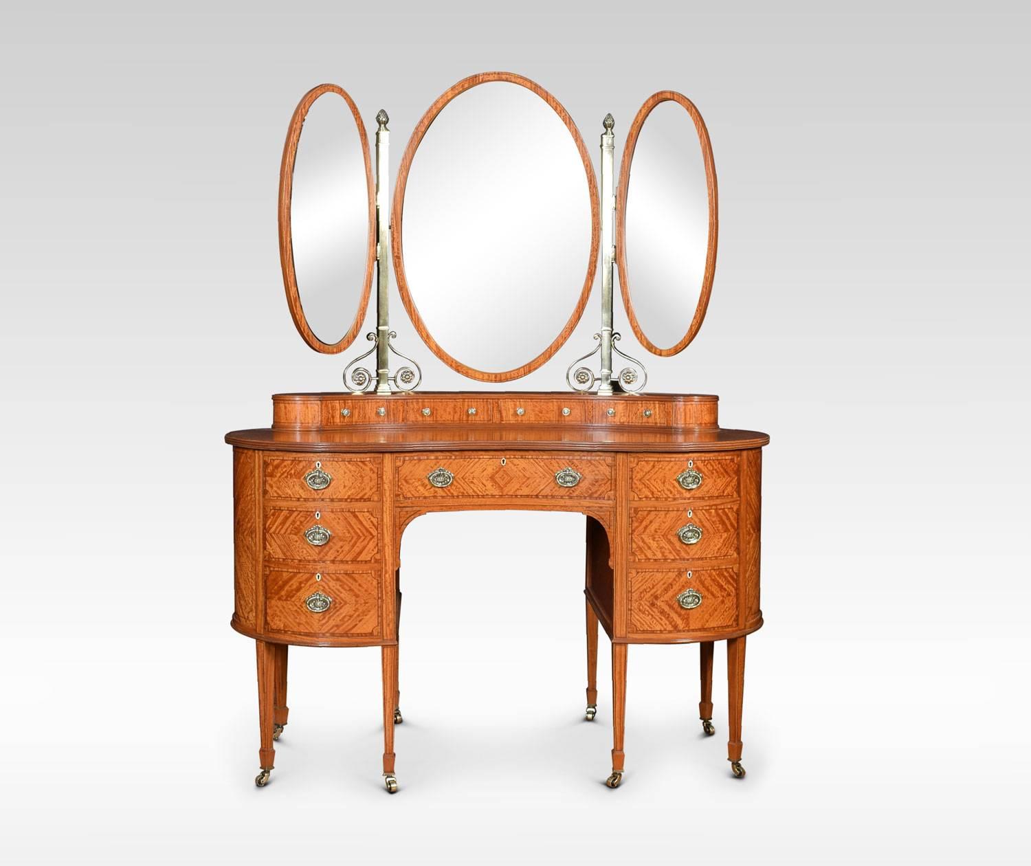 Satinwood string inlaid kidney shaped dressing table, having an ornate brass superstructure with acorn capitals. The central oval mirror having adjustable smaller mirrors to either side. Above three short draws with brass knob handles. The base with