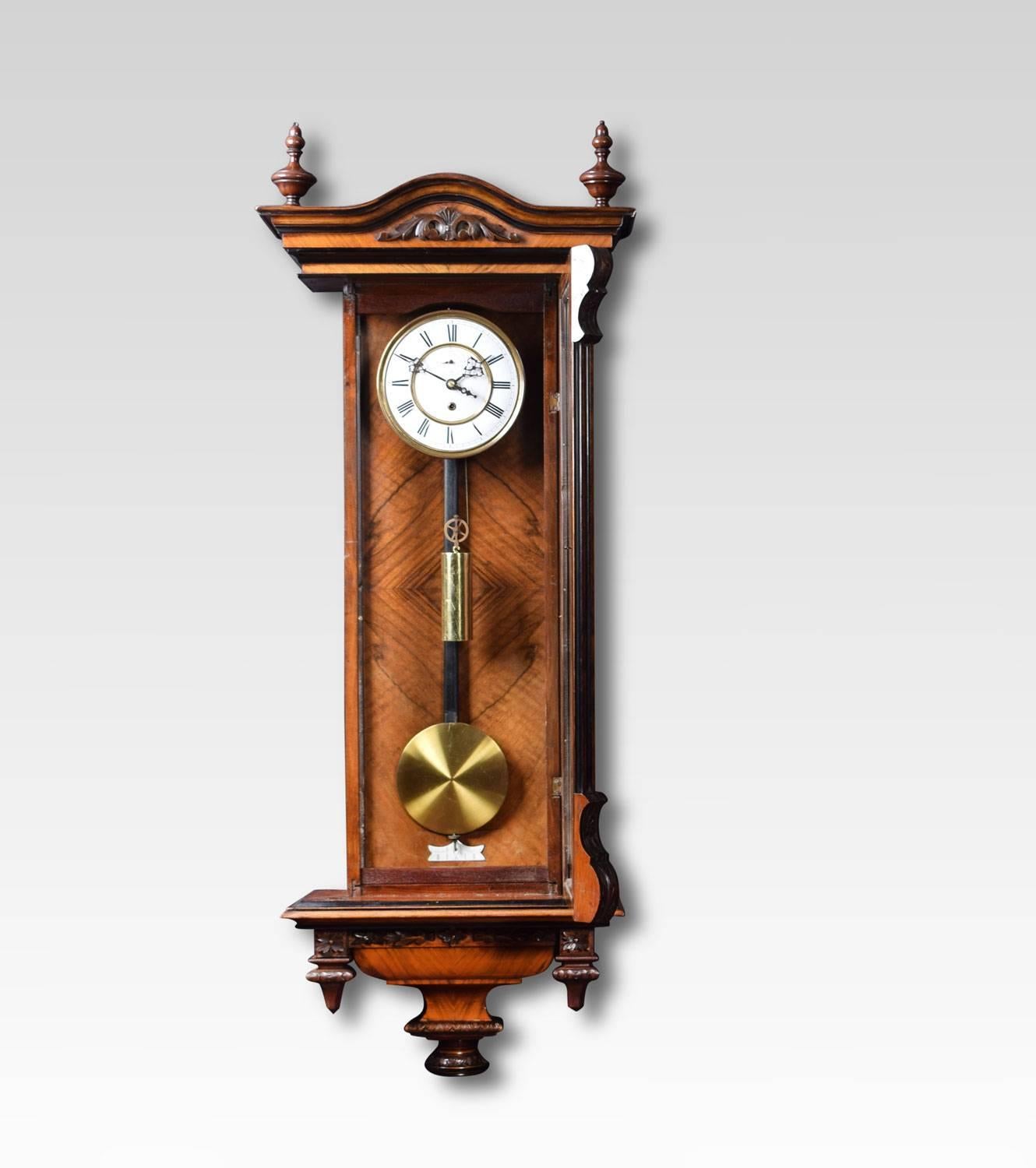 walnut and ebony Vienna wall clock the two part white enamel dial with Roman numerals and subsidiary seconds dial, with eight day movement with brass cased weight and similar pendulum,the walnut and ebonised case with cresting and turned decoration