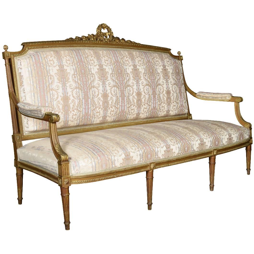French Louis XVI style giltwood three-seat settee the carved cresting top rail above large upholstered padded back, seat and arms raised up on turned fluted legs.

Dimensions:

Height 47.5 inches height to seat 16 inches

Width 73