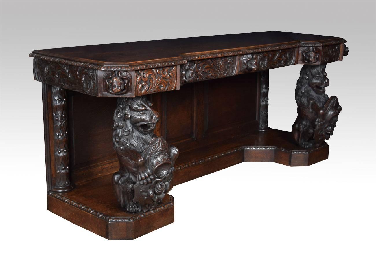 Large Victorian carved oak inverted breakfront sideboard, the large moulded top fitted with four frieze drawers set with carved angel mask capitals and raised up on two large lion carved supports each holding a rose capped shield above a inverted