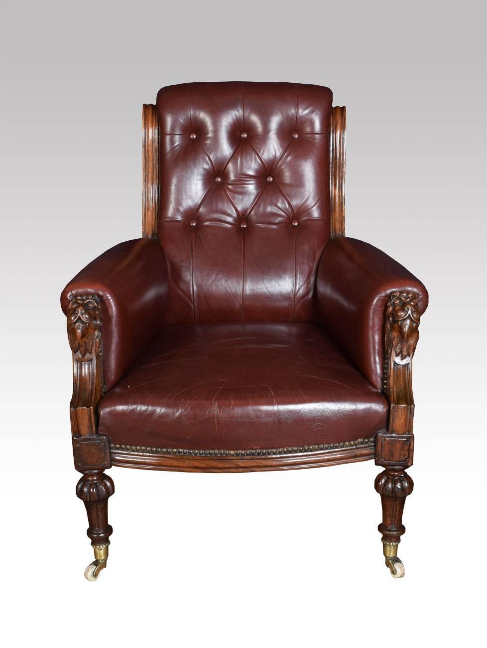 Victorian burgundy leather upholstered mahogany framed armchair the deep buttoned back above upholstered arms and seat with lions head finials all raised up on turned tapering legs terminating in brass caps and ceramic