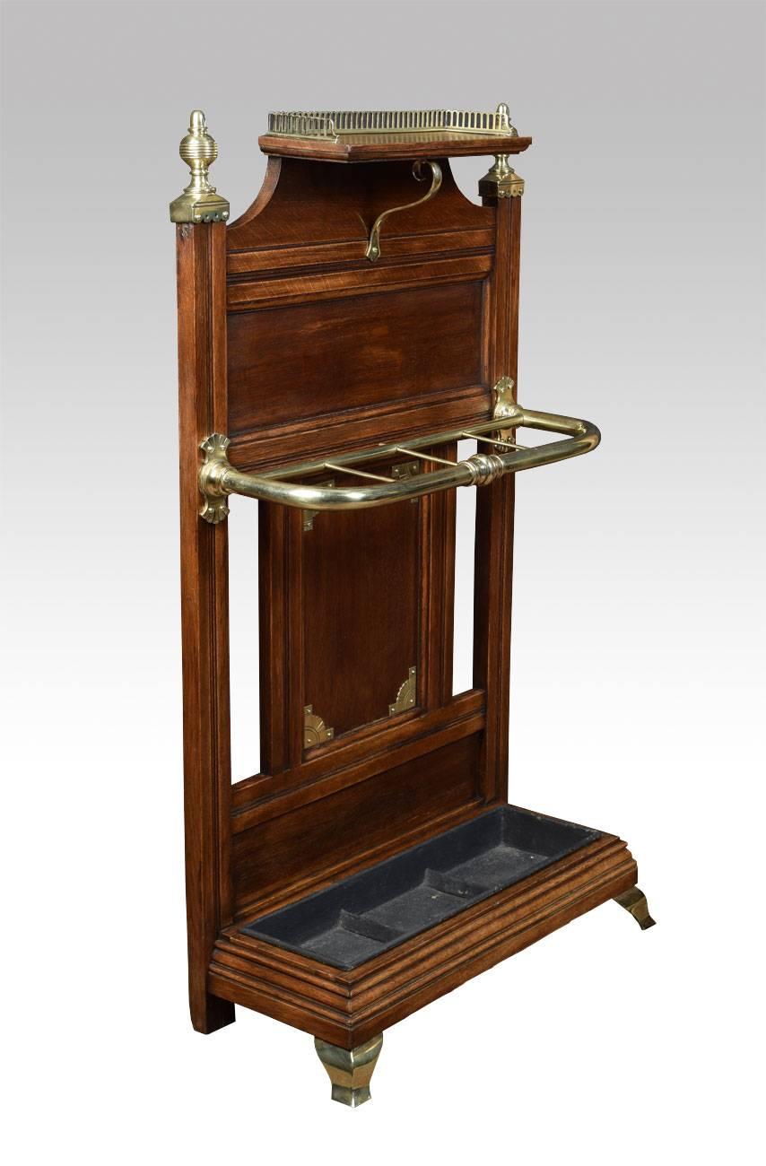 Victorian solid oak and brass mounted stick stand attributed to James Shoolbred and Co. Having raised three quarter gallery above a panelled back with turned brass finials and stick/umbrella holder to the moulded base supporting a drip pan. All