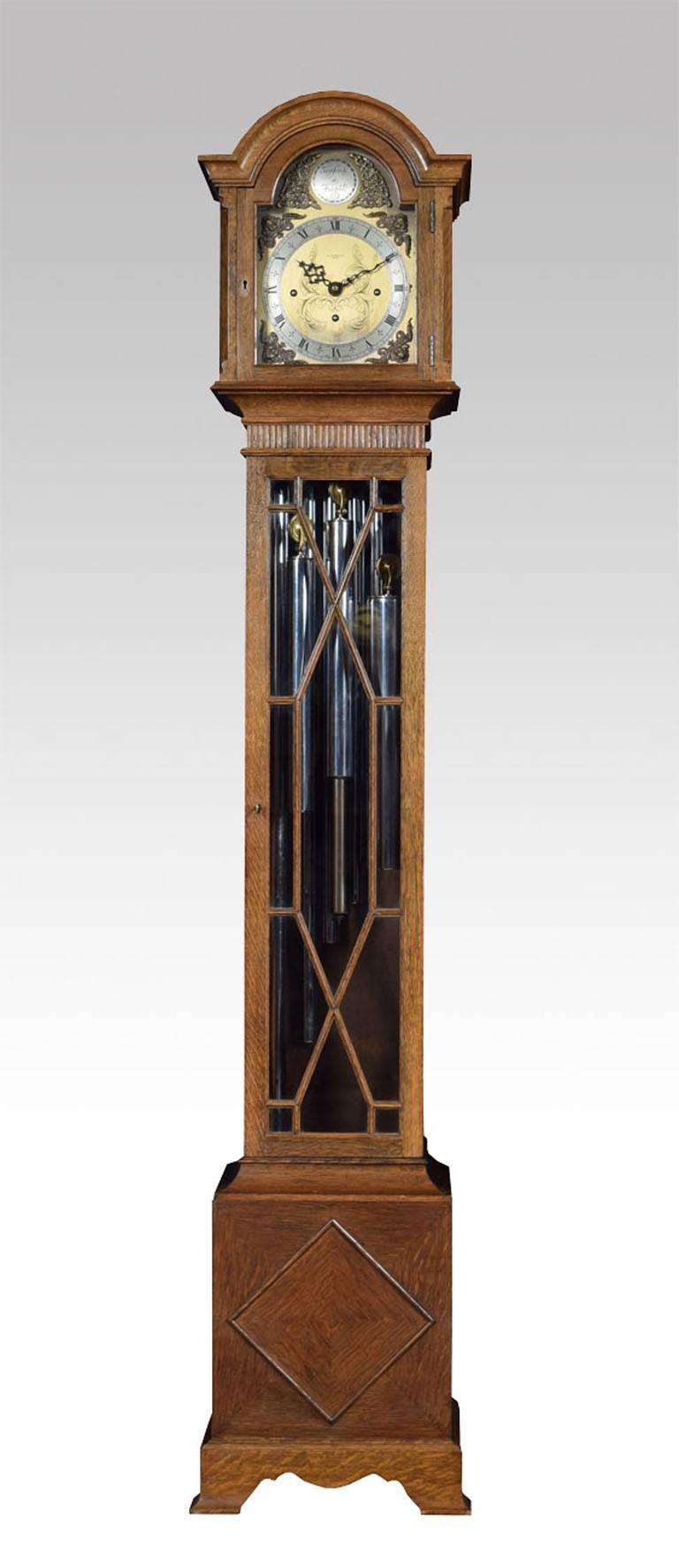 

Edwardian  Oak tube chiming clock, the eight-day tripple-train movement with anchor escapement and striking the hours and chiming the quarters on five chiming tubes, the arched brass dial engraved with gilt-metal Roman numerals and decorated