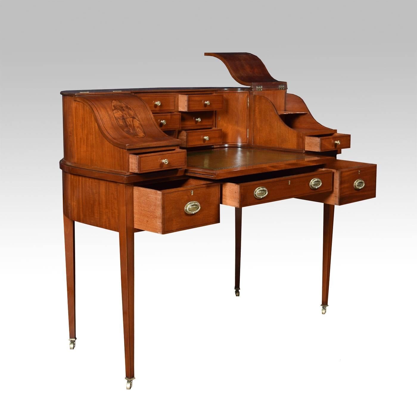 Mahogany Carlton house desk, the shaped upper structure with moulded edge above an arrangement of six small drawers, flanked by doors and down swept lidded compartments over a tooled and gilded green leather pull out writing surface. The frieze set