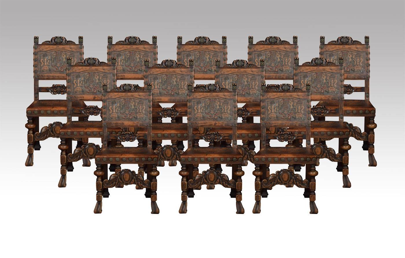 

Set of 14 Spanish walnut dining chairs comprising of two substantial carver and twelve singles, each with carved cresting top rail with central double headed eagle and crown motif, above leather multicolour embossed back and seat, secured with