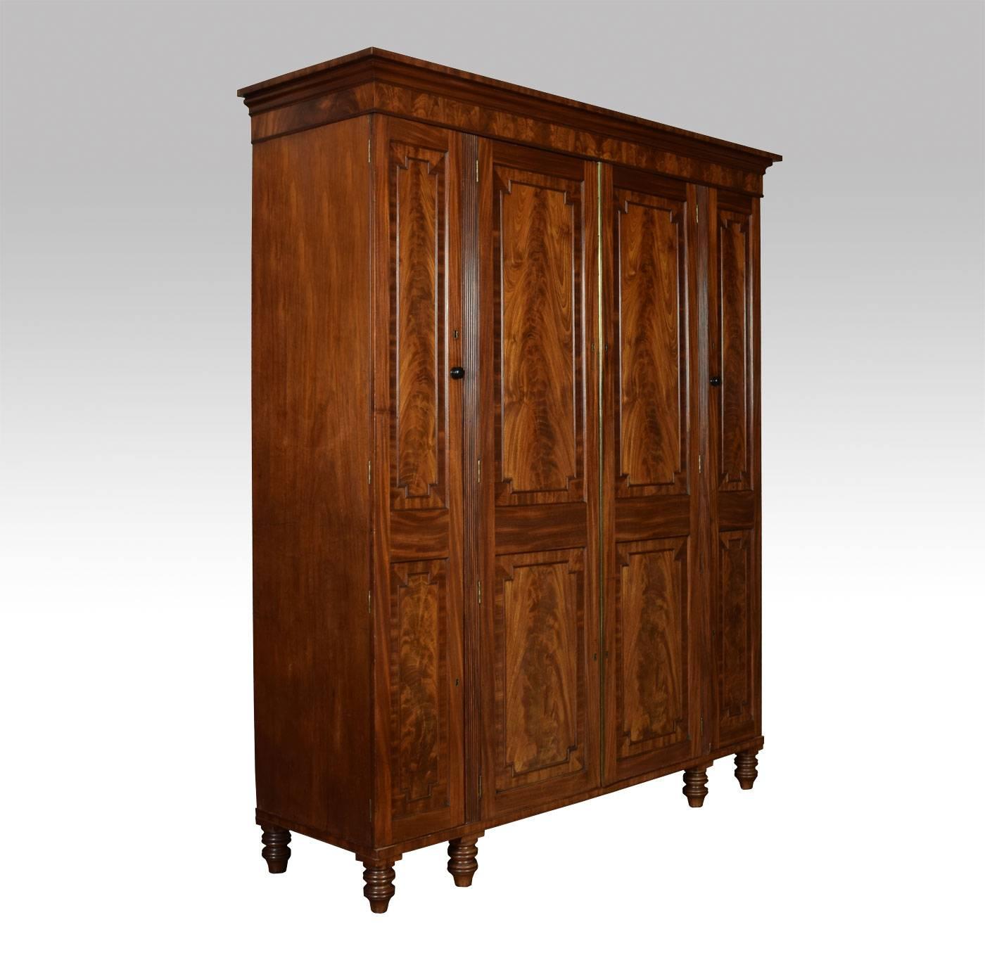 George IV mahogany wardrobe, attributed to Thomas Dowbiggin of Mount street. The moulded cornice above two central doors opening to reveal a press center with arrangement of sliding trays and draws below. The end sections with similar paneled doors