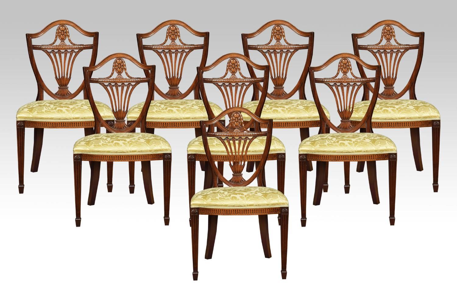 

Set of ten carved mahogany Hepplewhite style shield back dining chairs comprising of two armchairs and eight chairs with striking shield shaped backs and decorative pierced back splats with wheatsheaf design above overstuffed damask upholstered