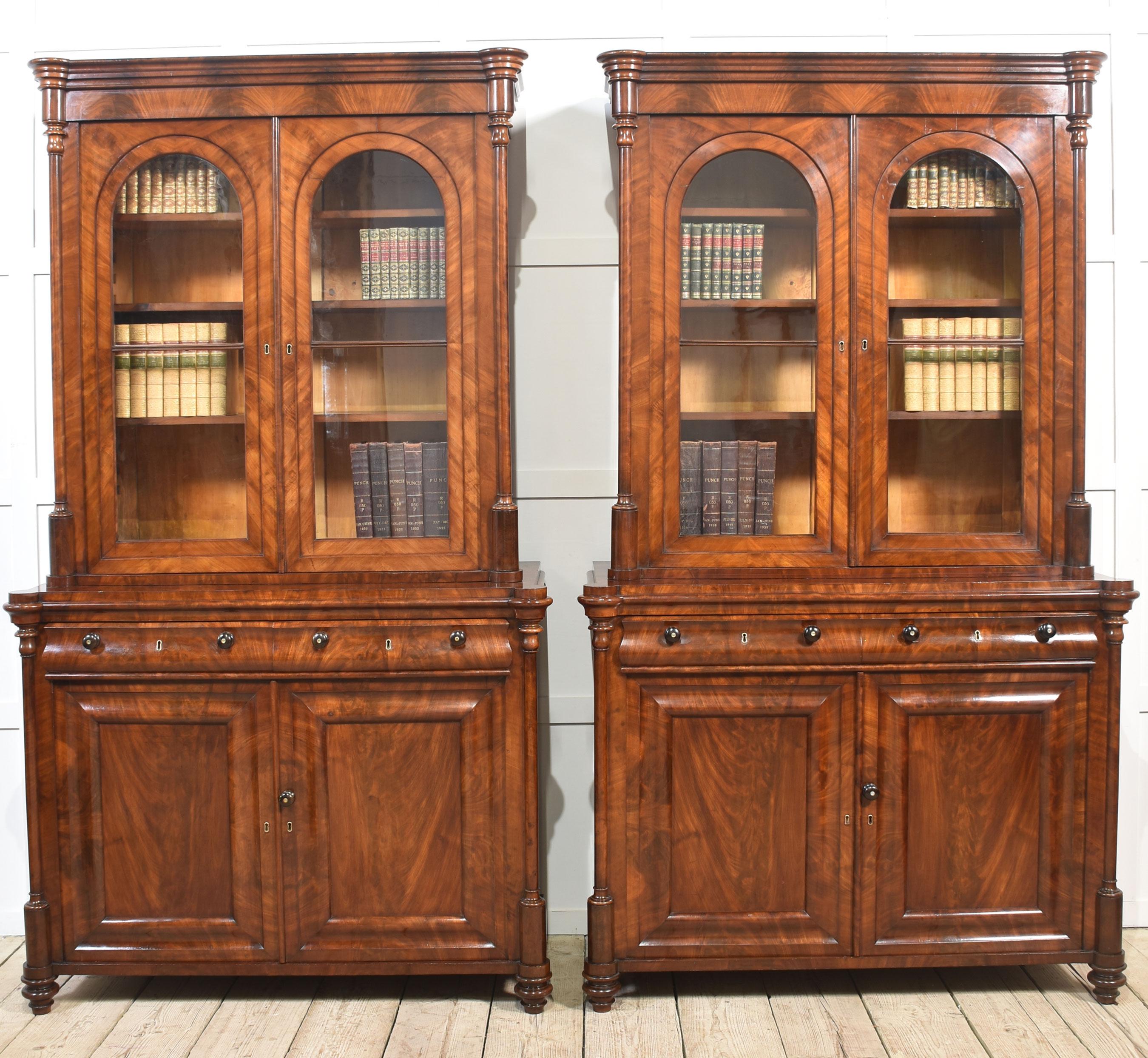 Coppia di librerie da biblioteca in mogano, ognuna con cornice modanata, sopra una coppia di porte vetrate pannellate che racchiudono interni a ripiani regolabili. Fiancheggiato da pilastri a tre quarti torniti.
La sezione di base è dotata di due