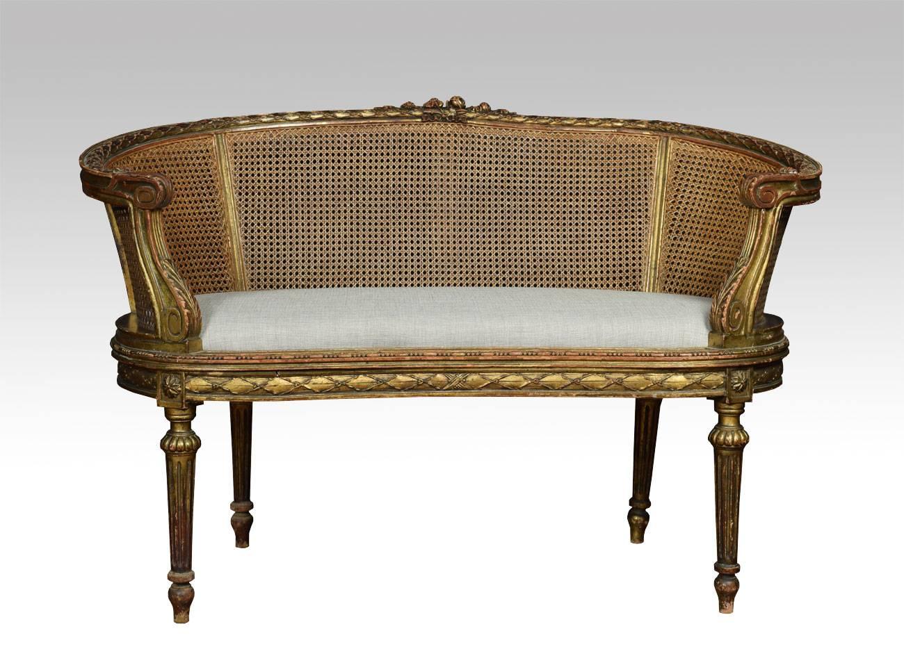 French Louis XVI style canapé settee, the carved rail in the typical manner of the period with highly detailed ribbon work along the crest among foliage, the frame a repeating motif of detailed leaves. To the scrolling acanthus caped arms, flanking