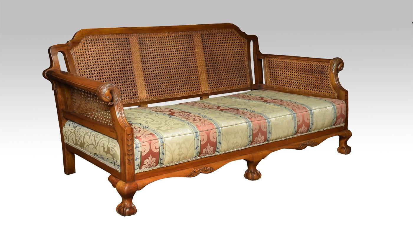 

Three piece walnut framed lounge suite comprising of three-seat couch and pair of armchairs, with bergere paneled back and sides, flanked by out swept scrolling eagle headed arms. All raised on short cabriole legs terminating in claw and ball