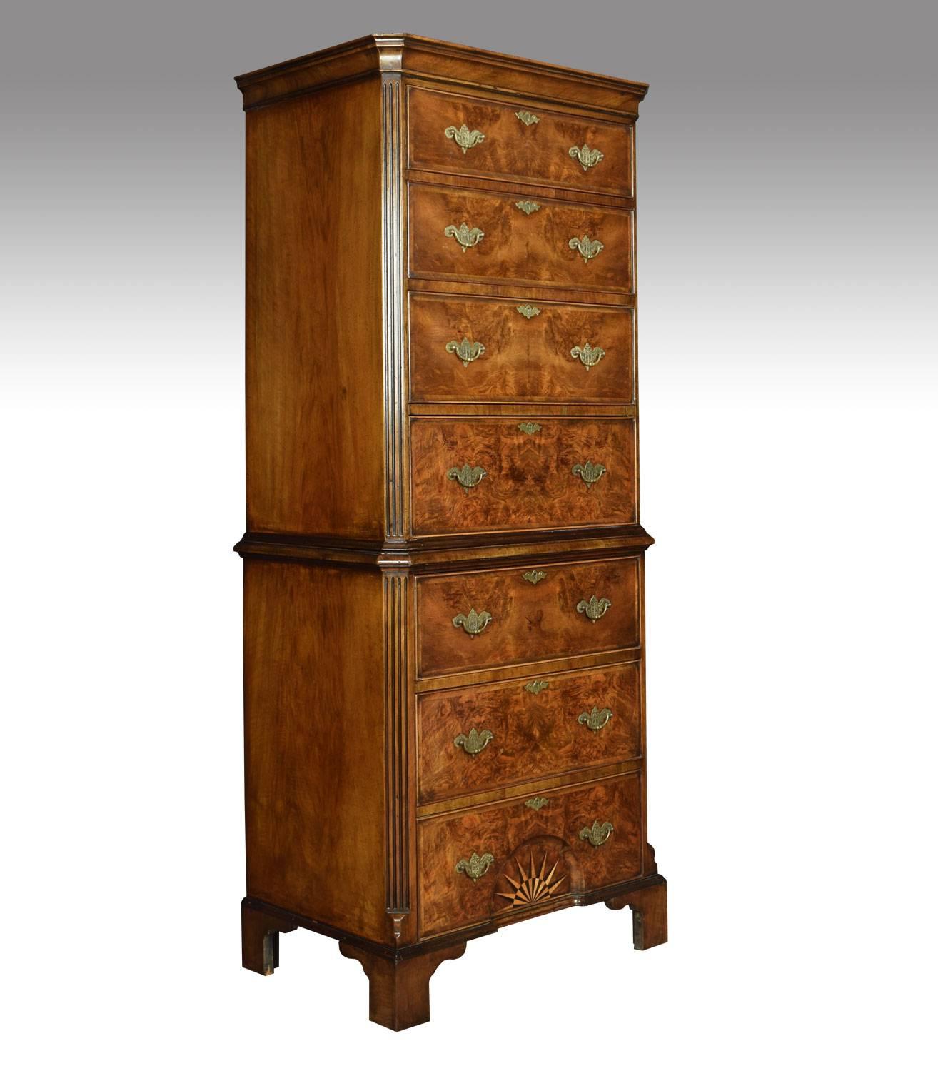 Figured walnut chest on chest, the upper section of four graduated drawers with brass tooled handles and oak lined draws, seated on lower section of three conforming graduated drawers, the lower drawer with centralized concave recess decorated with