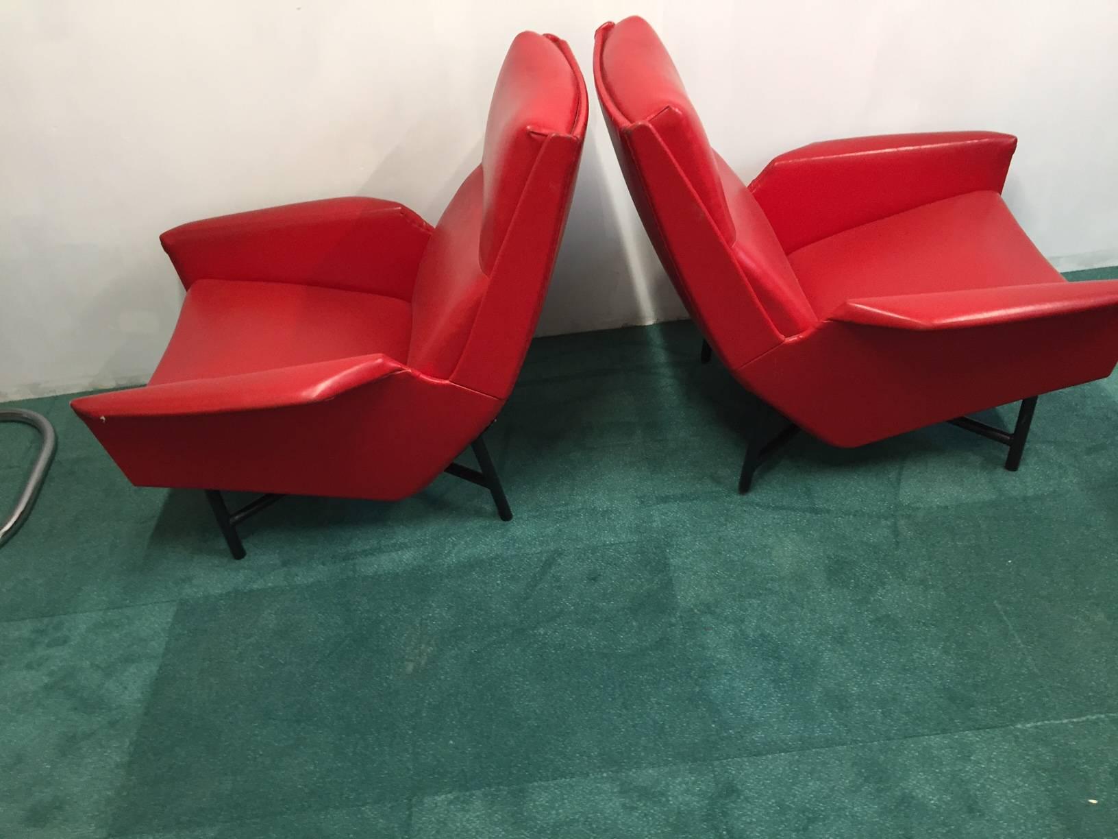 Two Claude Delor armchairs in red simili and brass feet.