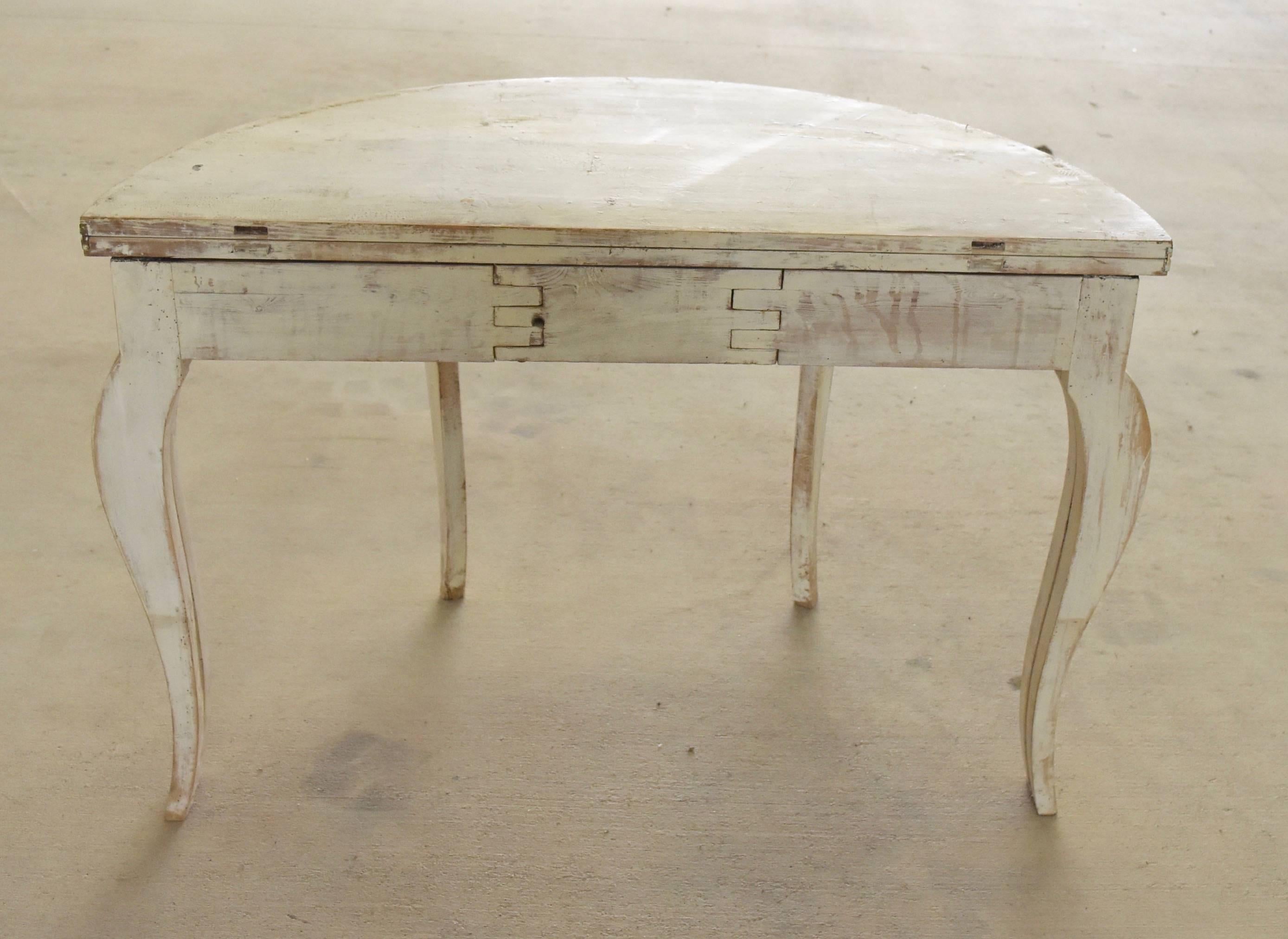 This Swedish demilune table is painted white and scraped back. It's made from pine, makes into a round table as well and can seat up to six people with small chairs.