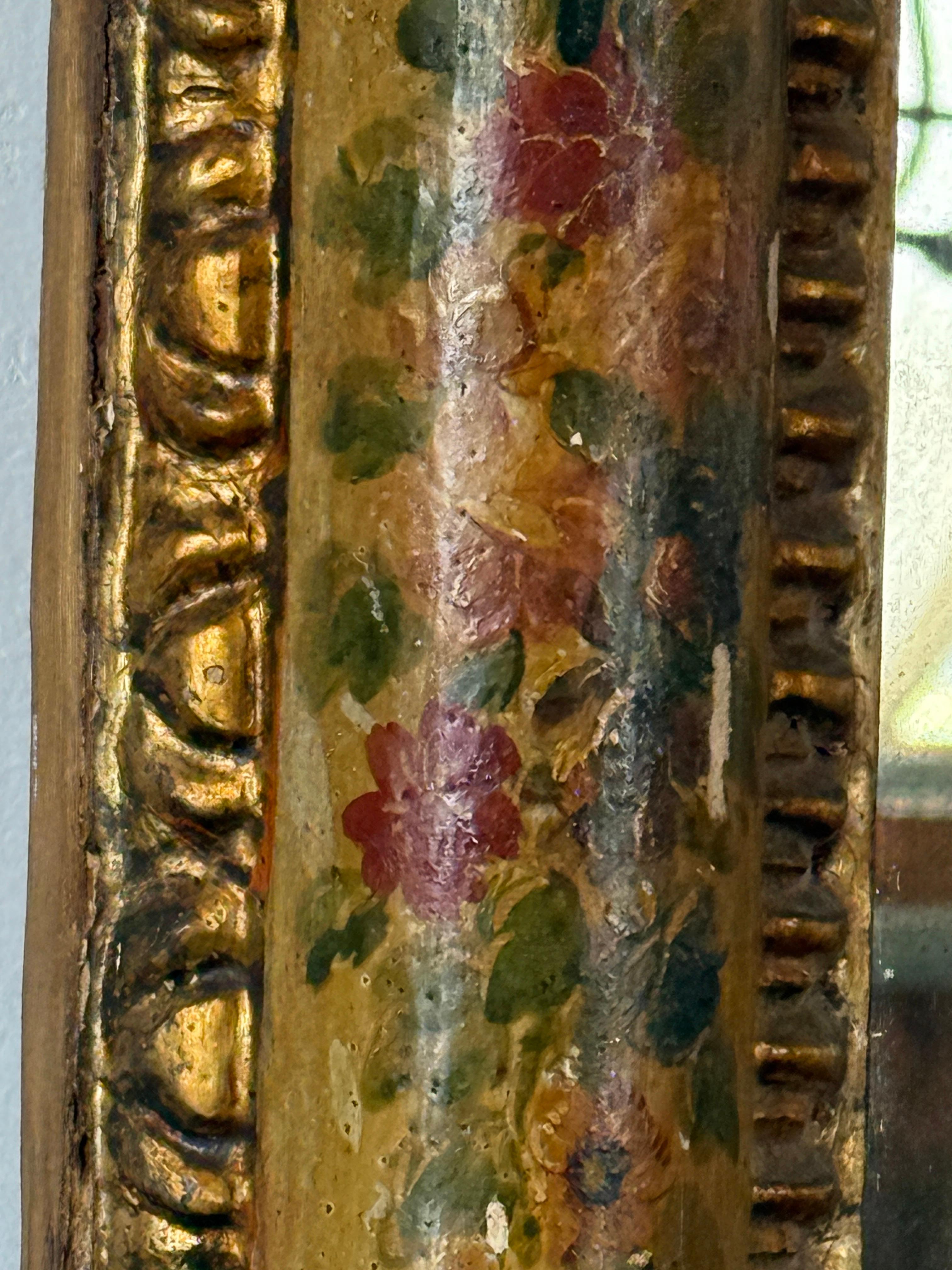 Il s'agit d'un magnifique miroir vénitien peint en rouge, datant du 19e siècle, dont la vitre a été remplacée. Il a un fond jaune avec des fleurs rouges peintes et des tiges vertes autour du miroir, ce qui lui donne une charmante impression de