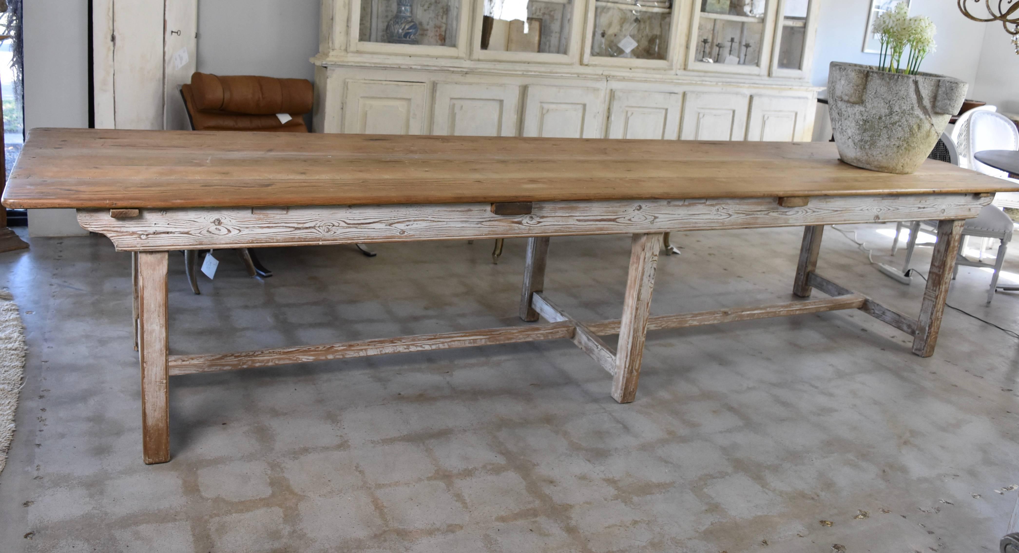 This is French, late 19th century to early 20th century farm table that's pegged, Pine with a painted or washed white base. It easily seats 10 people with large chairs or up to 14 with smaller chairs. It's very sturdy and no problem for guest to
