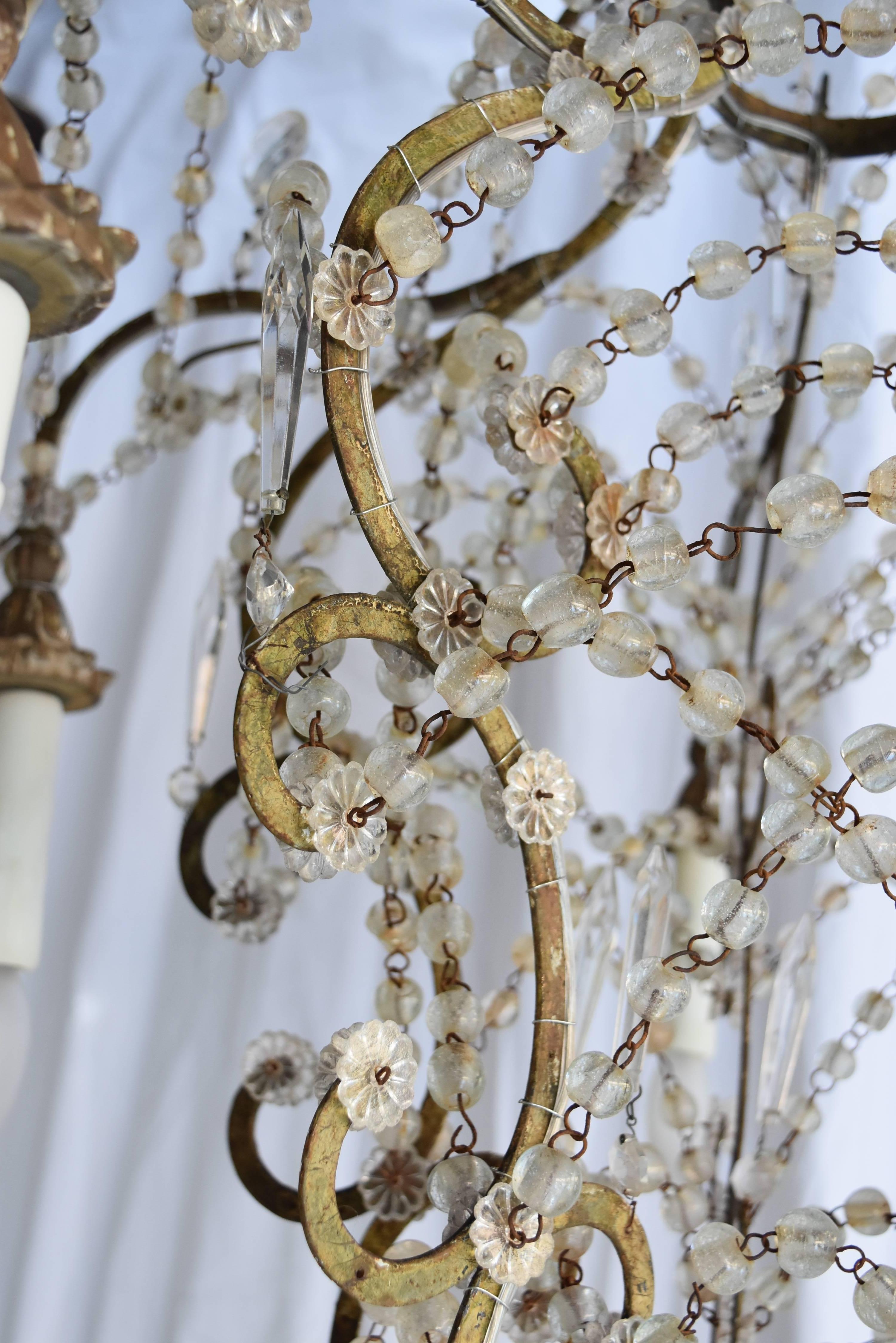This beautiful Italian chandelier is early 19th century and features draped blown crystals with wooden gilt bobeches.
