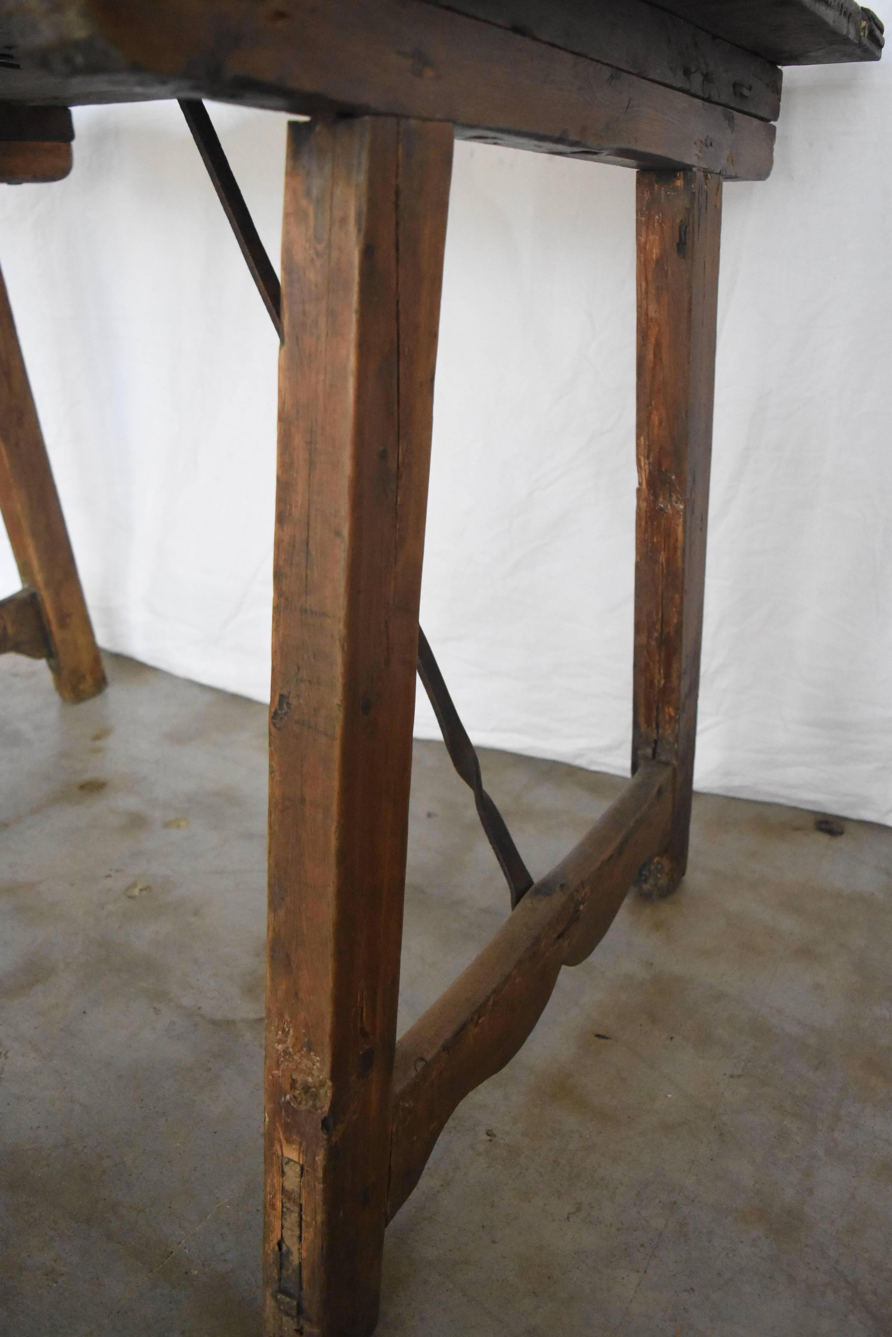 This is a rustic, early table from Spain. It has both walnut top, chestnut legs, beautiful scalloped legs on the bottom and iron stretcher; which has been changed at some point. I took photos of it underneath so you could see the bottom of the top