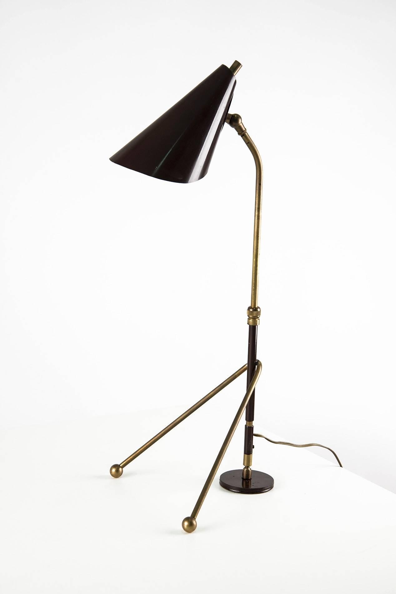 Brilliant and rare table lamp manufactured in Italy in the 1950s. This lamp can be easily adjusted and tilted thanks to its sliding metal tube and the joints located on the base and on the shade. Black lacquered metal base and shade, brass structure