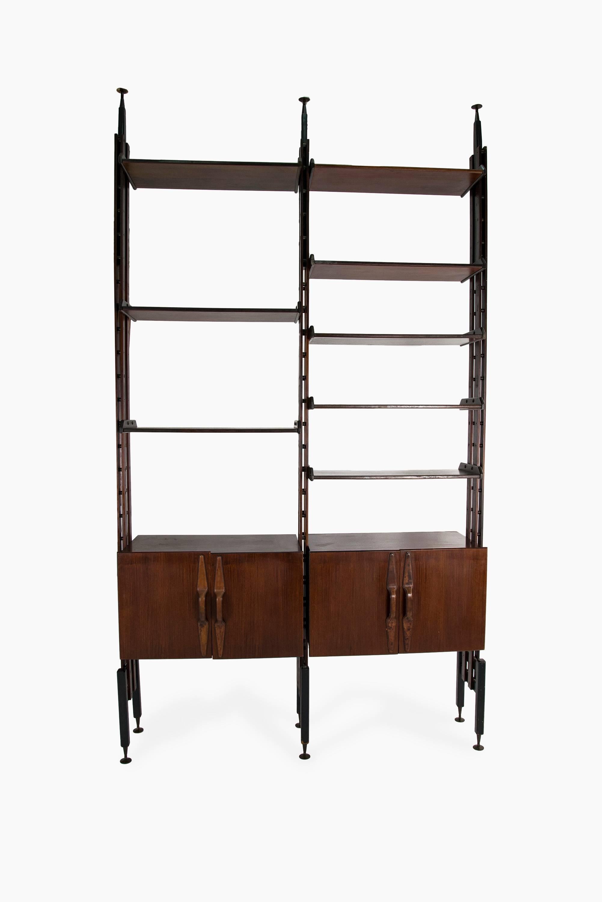 Large organic floor to ceiling bookcase manufactured in Italy in the late 1950s. Rosewood structure with two cabinets and eight shelves, brass feet, leather handles. The shelves and cabinets can be mounted with the preferred configuration, the