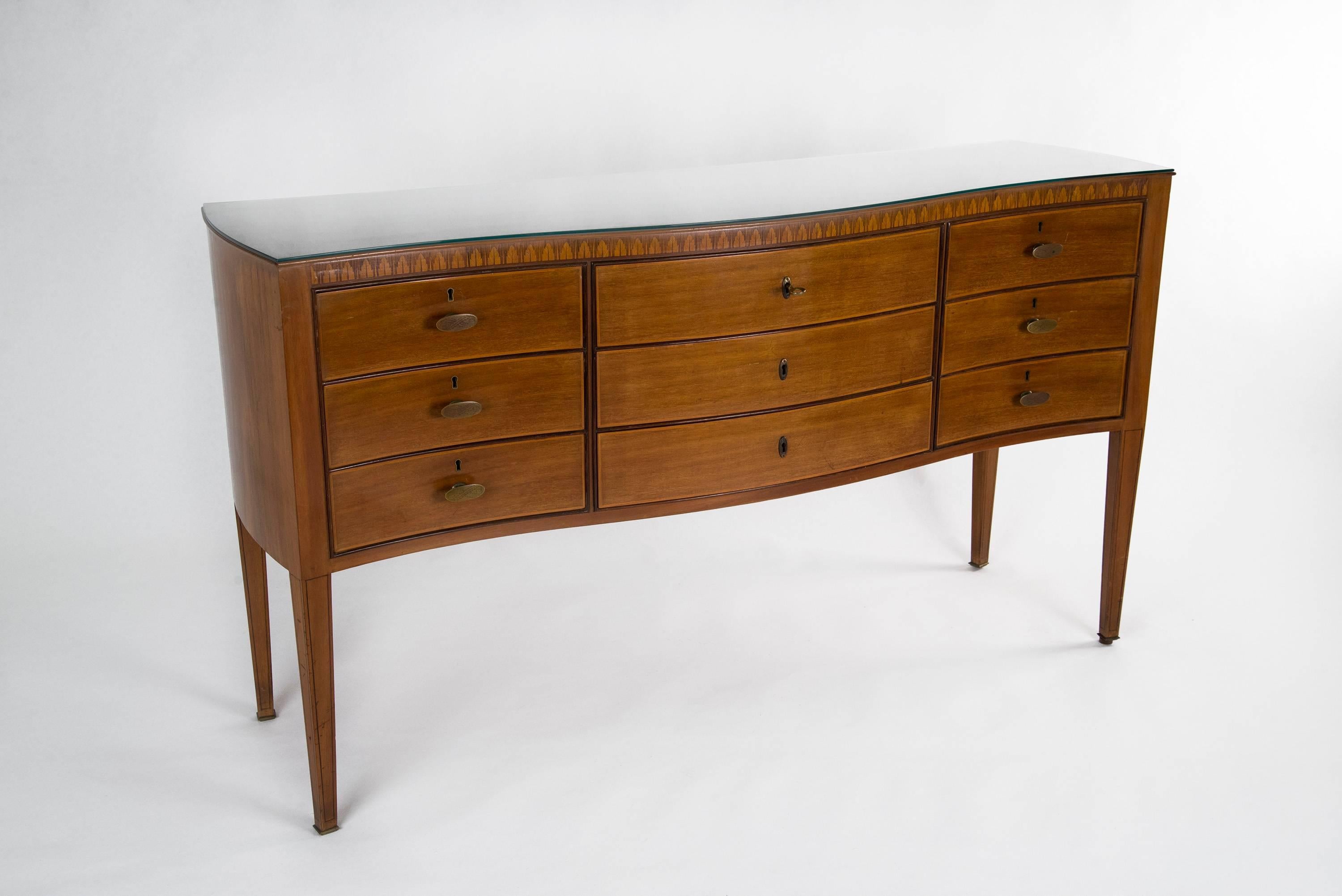 Elegant chest of drawers designed by Paolo Buffa, manufactured in Italy in the 1950s. Wooden structure with exquisite inlaid decorations and beautiful curved shape, carved brass handles, glass top (which can be removed), brass sabots. Good original