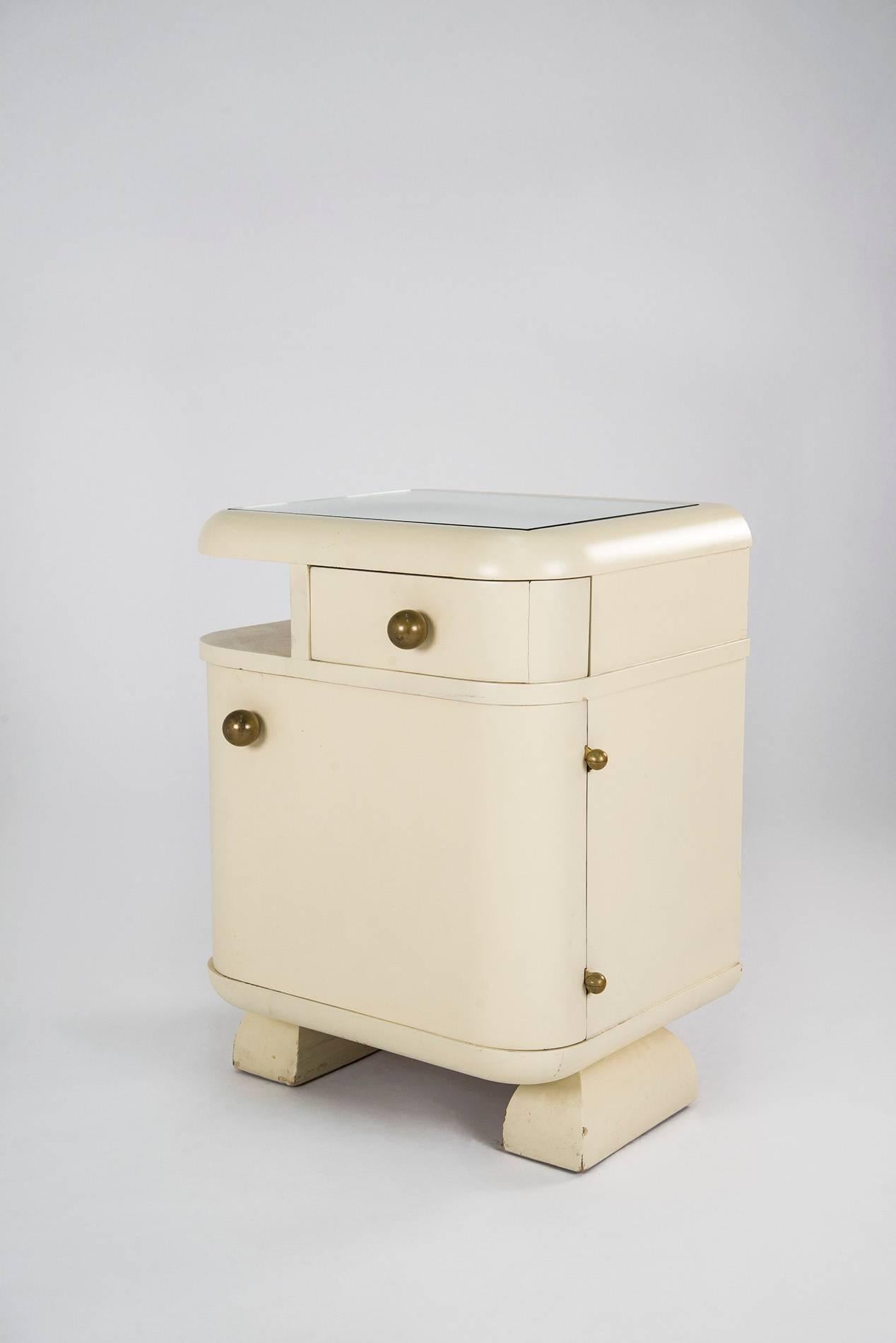 Pair of extraordinary Art Deco nightstands manufactured in Italy in the 1930s. White lacquered wooden structure featuring one drawer and one door with internal shelf, glass top, brass handles and joints. Good original vintage conditions.