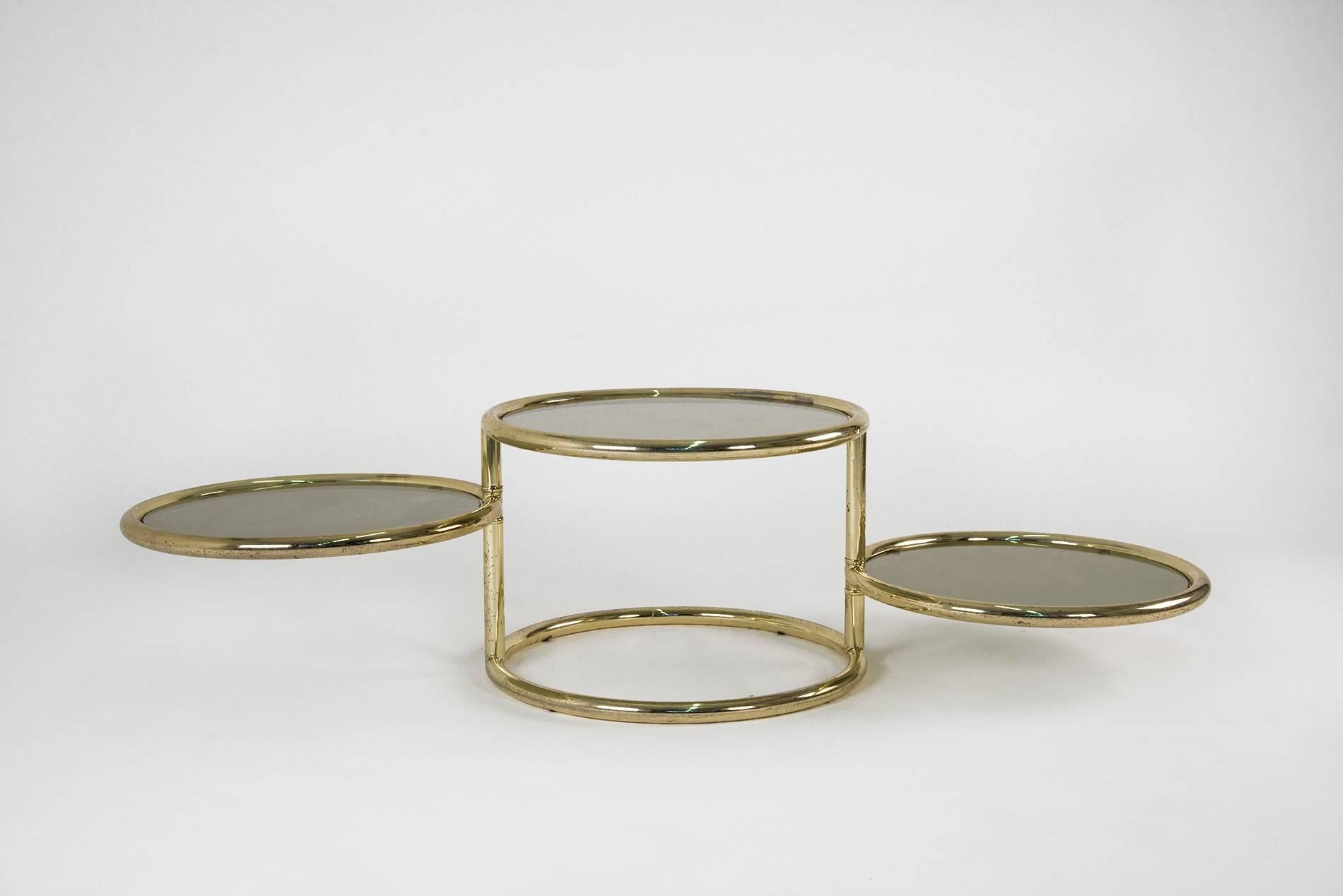 Pair of low tables in brass with smoked glass pivoting trays in the style of Milo Baughman, manufactured in Italy in the 1970s. Good original vintage conditions. When all the trays are extended, maximum width is cm 169. They can be sold separately.