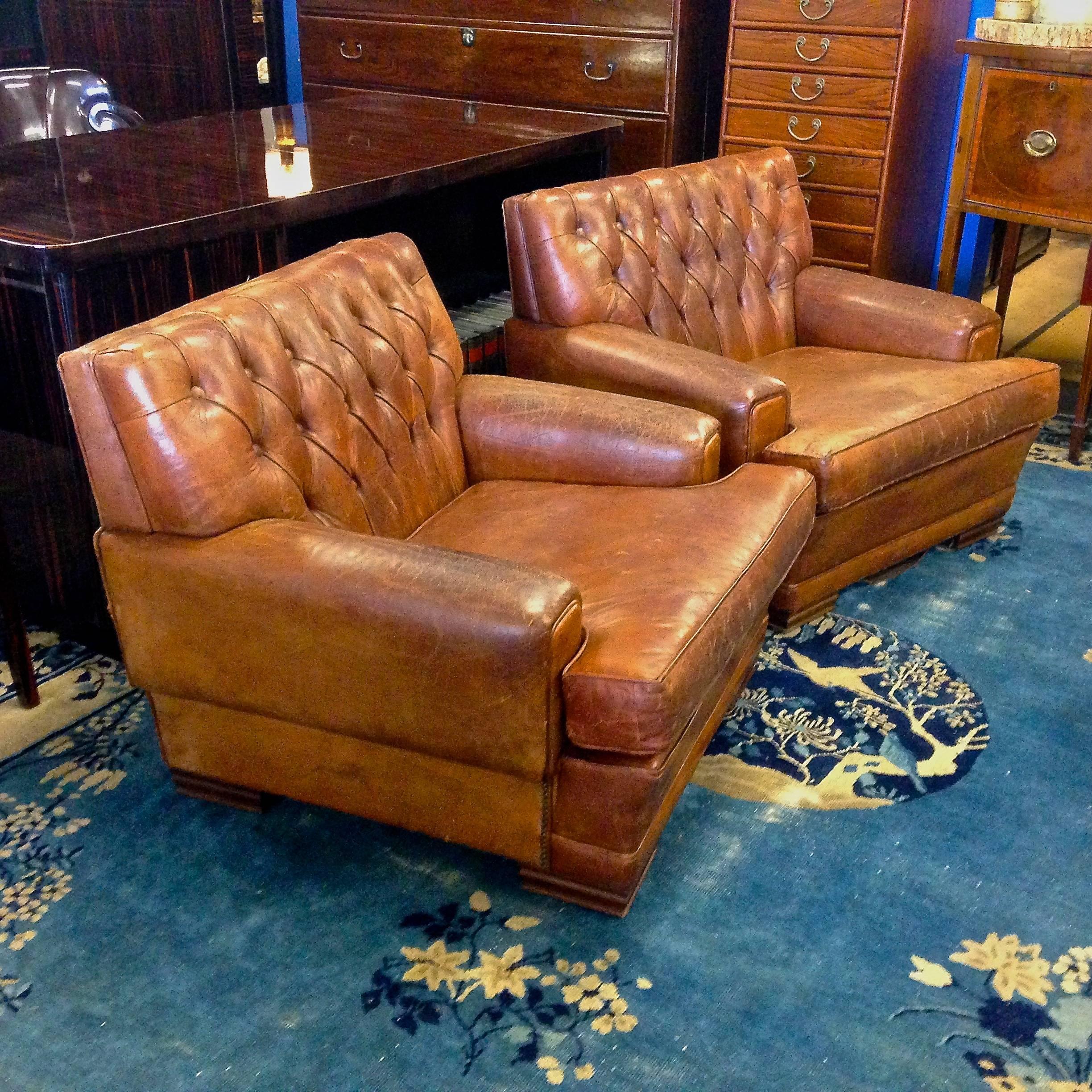 Pair of original 1920s French Art Deco button tufted leather club chairs. The original leather has become patinated and uniquely distressed with age. The chairs are in excellent sturdy physical condition. There are 18 button tufts on each chair.