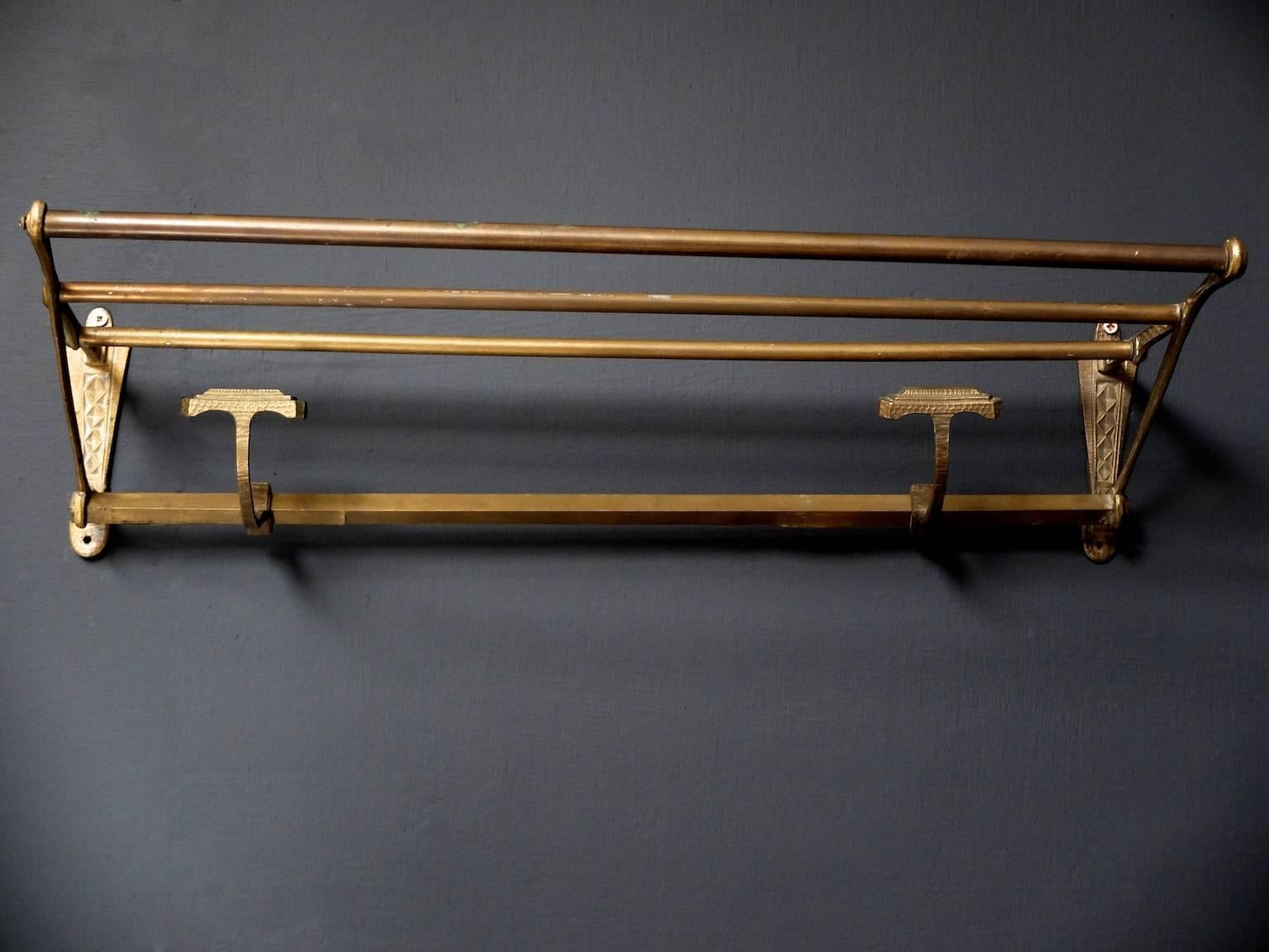 A brass wall-mounted hat and coat rack.

Two sliding coat hooks,

French, 1920s.

Measures: H:16 W:58 D:22 CM.