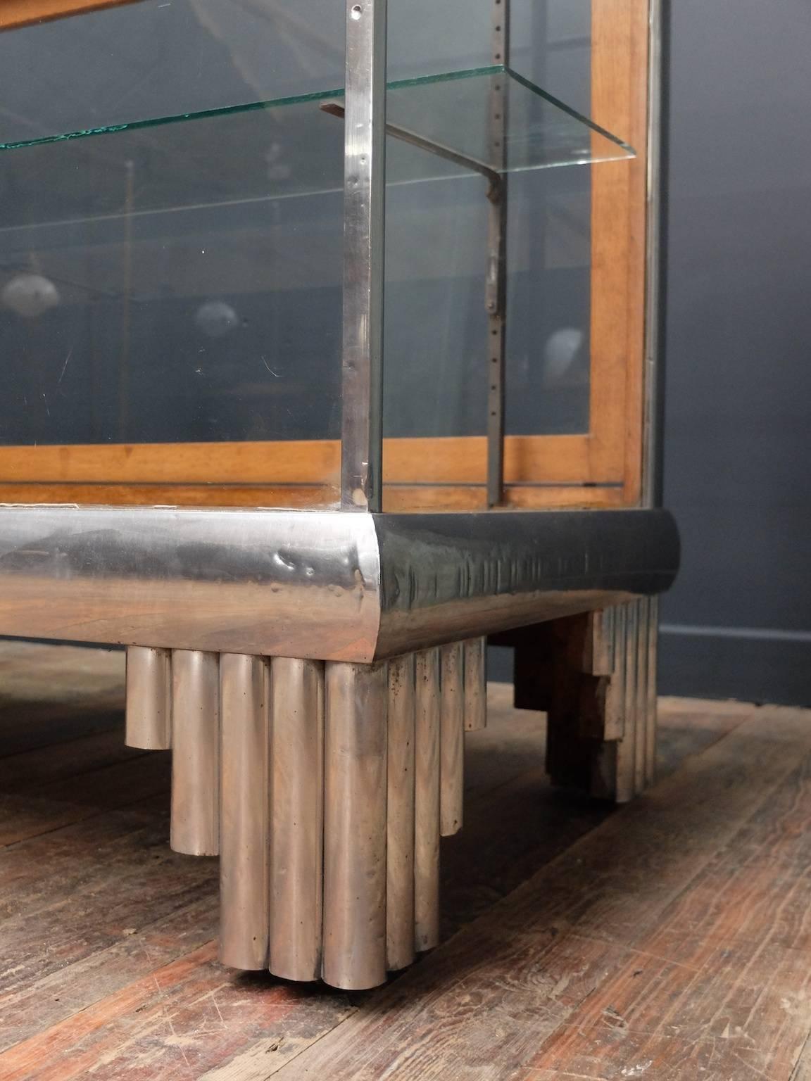 A glazed shop display counter in the Art Deco taste.

Polished alloy wrapped timber frame, two sliding doors to the rear, single glass adjustable shelf to the interior.

English, 1920s.