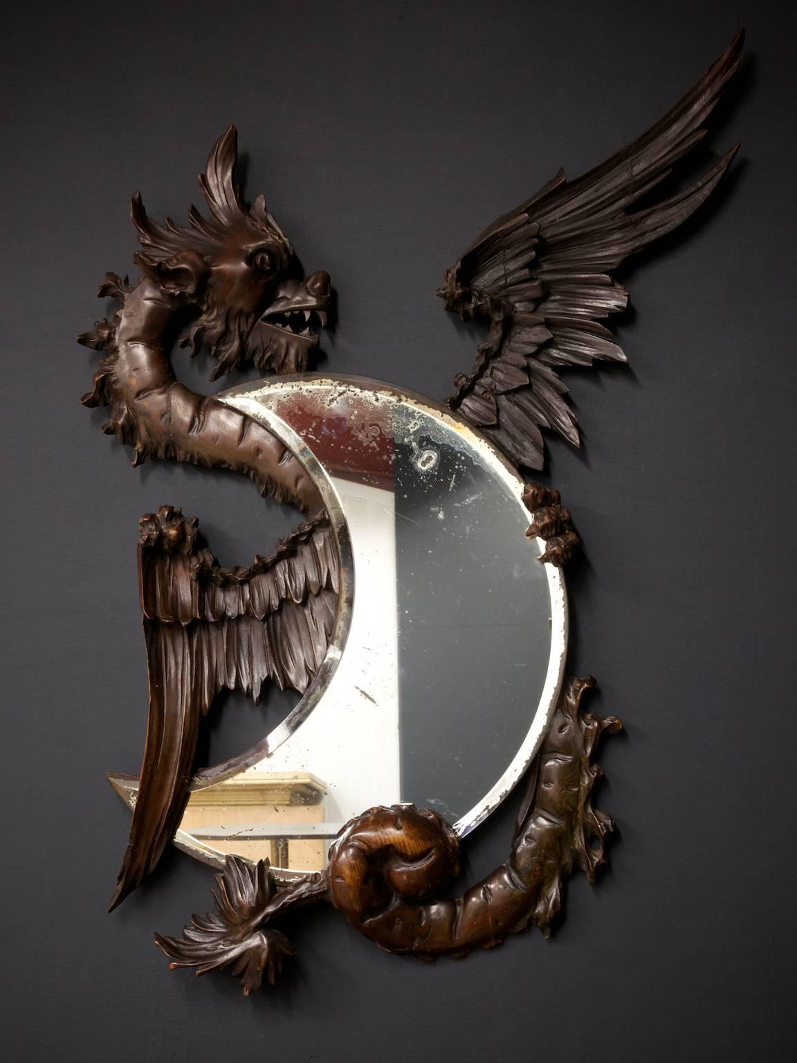 A carved mirror in the form of a Chinese dragon holding a crescent moon mirror.

Elaborately carved French walnut 