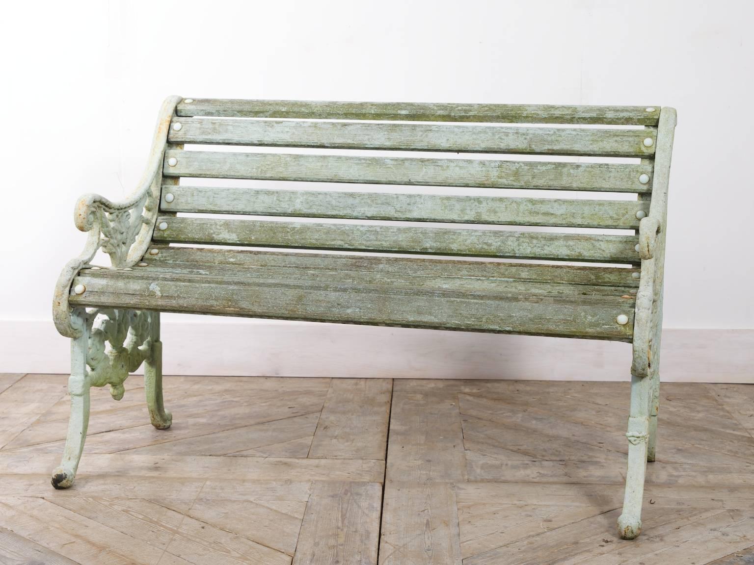 A two-seat garden bench.

Ornate cast iron end supports with timber seat, wonderful color.

Old repair to the base of one leg.

English, circa 1900.
  