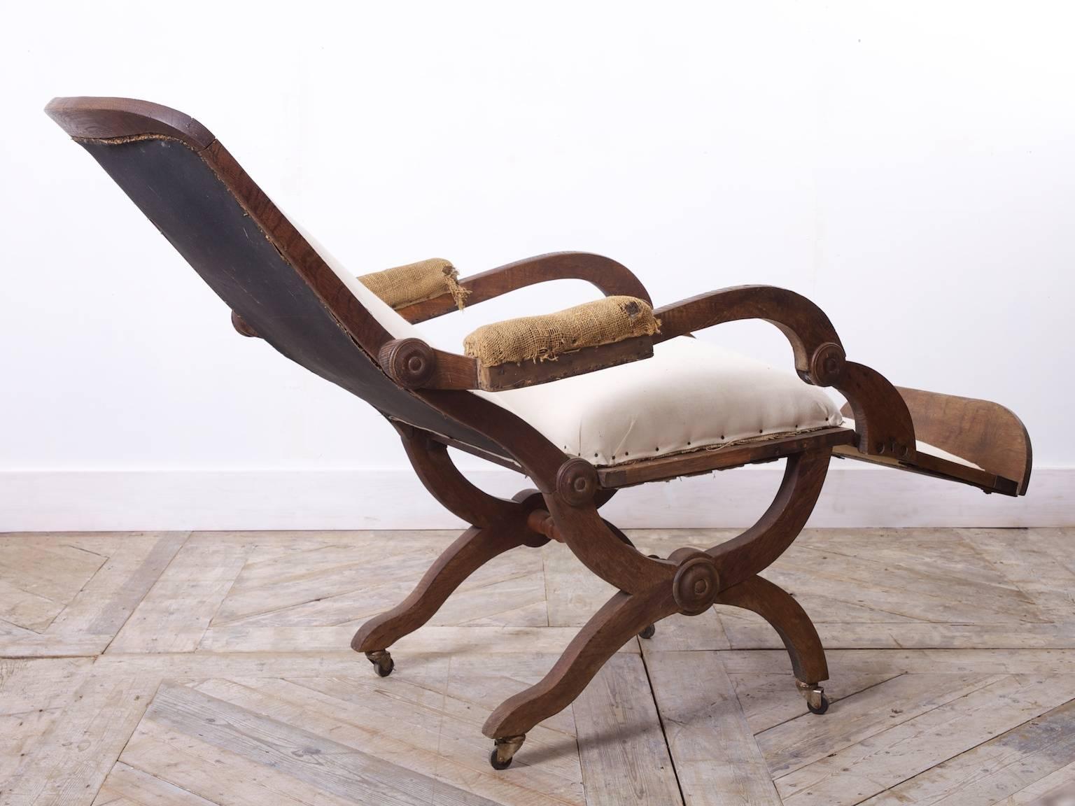 A oak reclining armchair.

The frame has an upholstered arm, seat, backrest and leg support.

The X-frame base raised on brass caster,

French, circa 1890. 

Fully reclined D:130 CM.