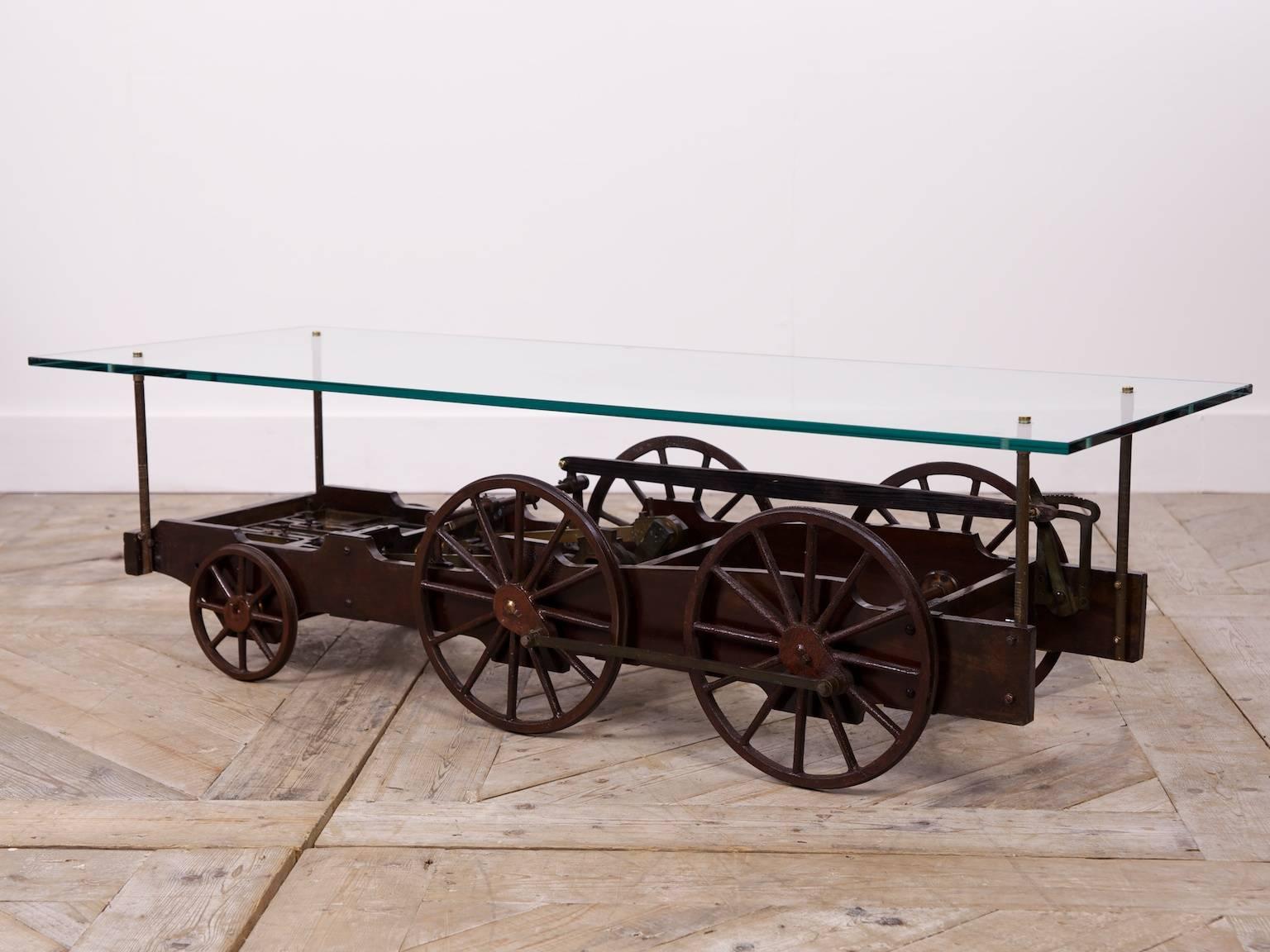 A museum scale model of a steam train chassis.

Beautifully engineered piece. Mahogany frame with steel bronze and brass moving parts.

The thick glass coffee tabletop is easily removed.
 