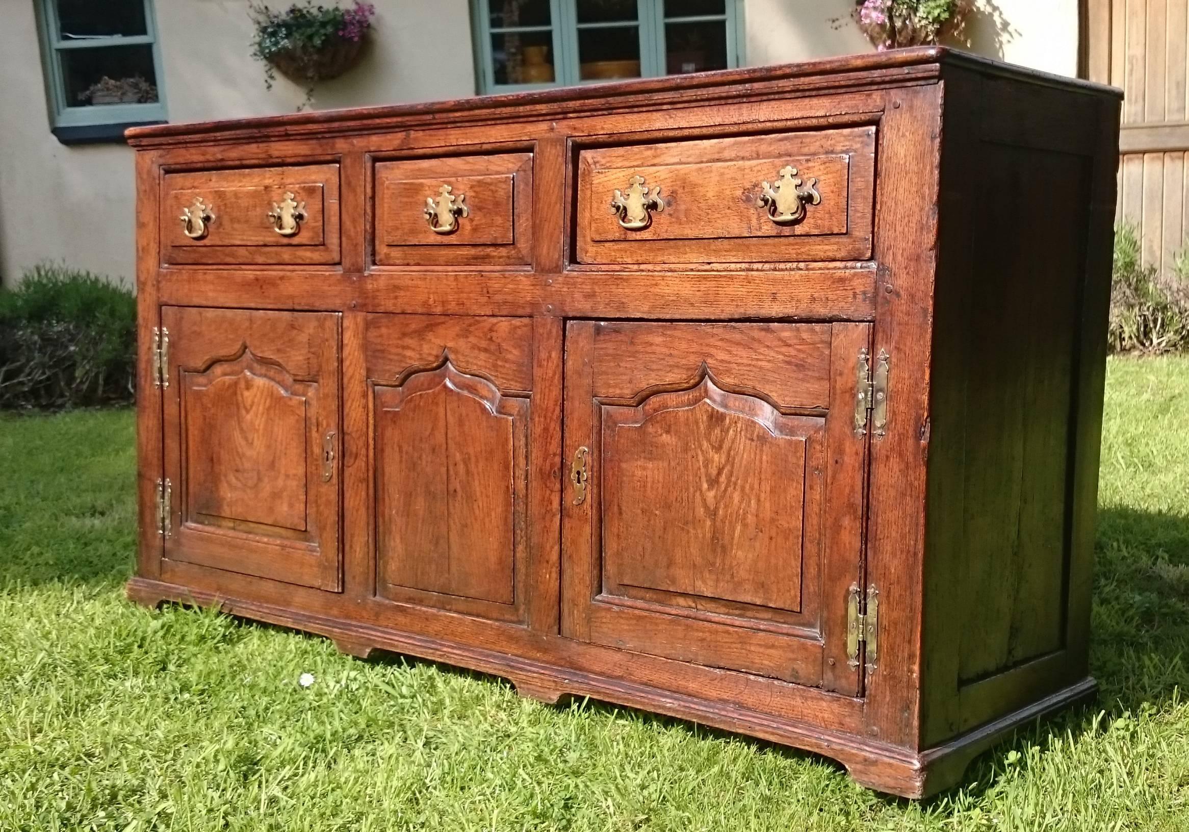 18th century antique oak dresser with three drawers over two cupboards. This dresser has lots of storage space and the timber has faded to a rich golden brown colour with a deep patination. This is a very fine piece of furniture with lovely faded