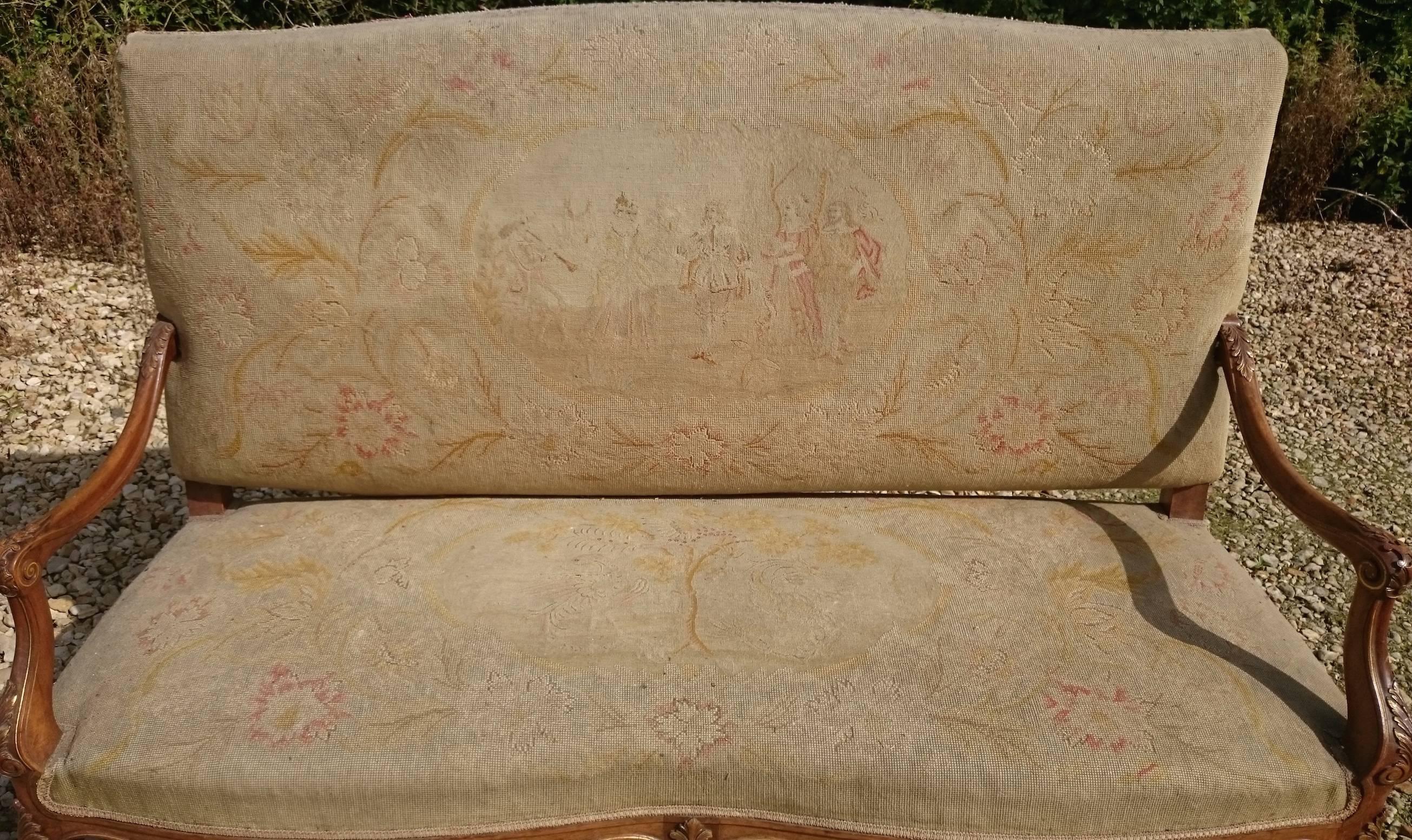 Charming French upholstered settle with walnut show wood and traces of the original gilding standing on elegant cabriole legs and with generous shape to the arms to match the leg and stretchers underneath, covered in what may be the original fabric