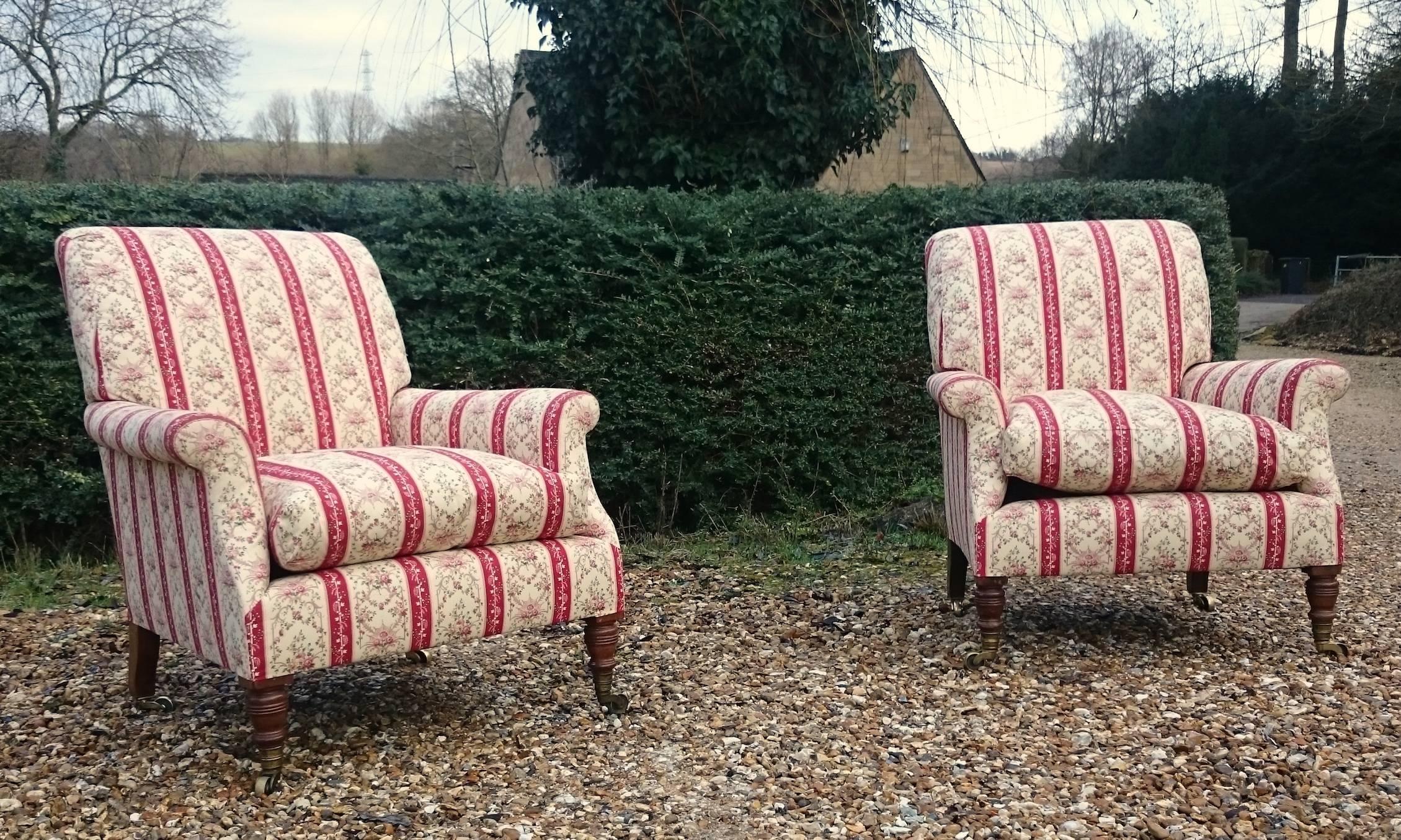 Pair of antique upholstered library chairs made by Howard and Sons. These chairs stand on tall turned legs with the ring turns and cups specific to Howard. This pair are extremely comfortable standing slightly higher that the Bridgewater model they