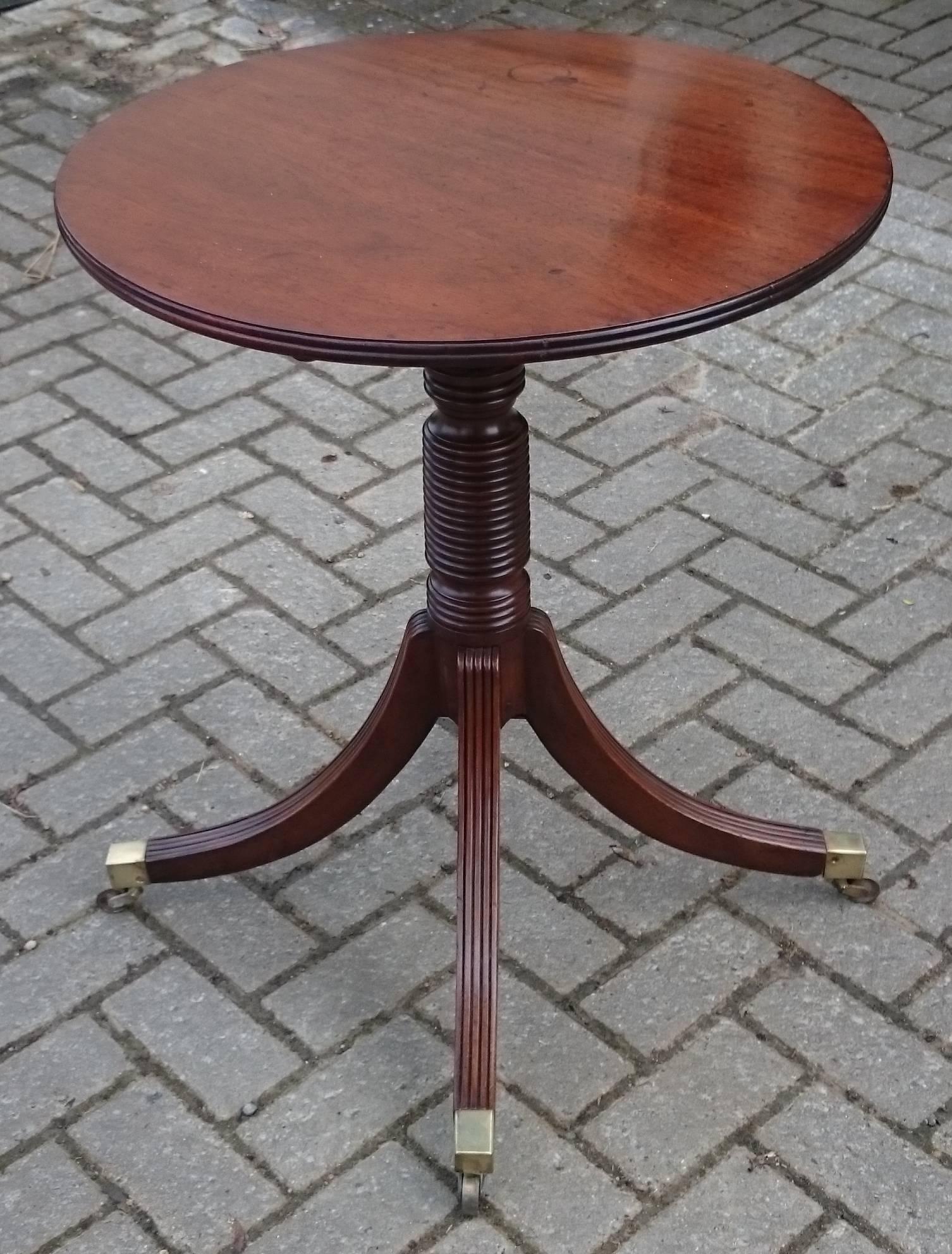Antique mahogany wine table or lamp table with very elegant turned and reeded base with an unusually generous number of ring turns to the column and lots of reeds on the top of the legs. The edge of the top is also reeded. The whole table is made of